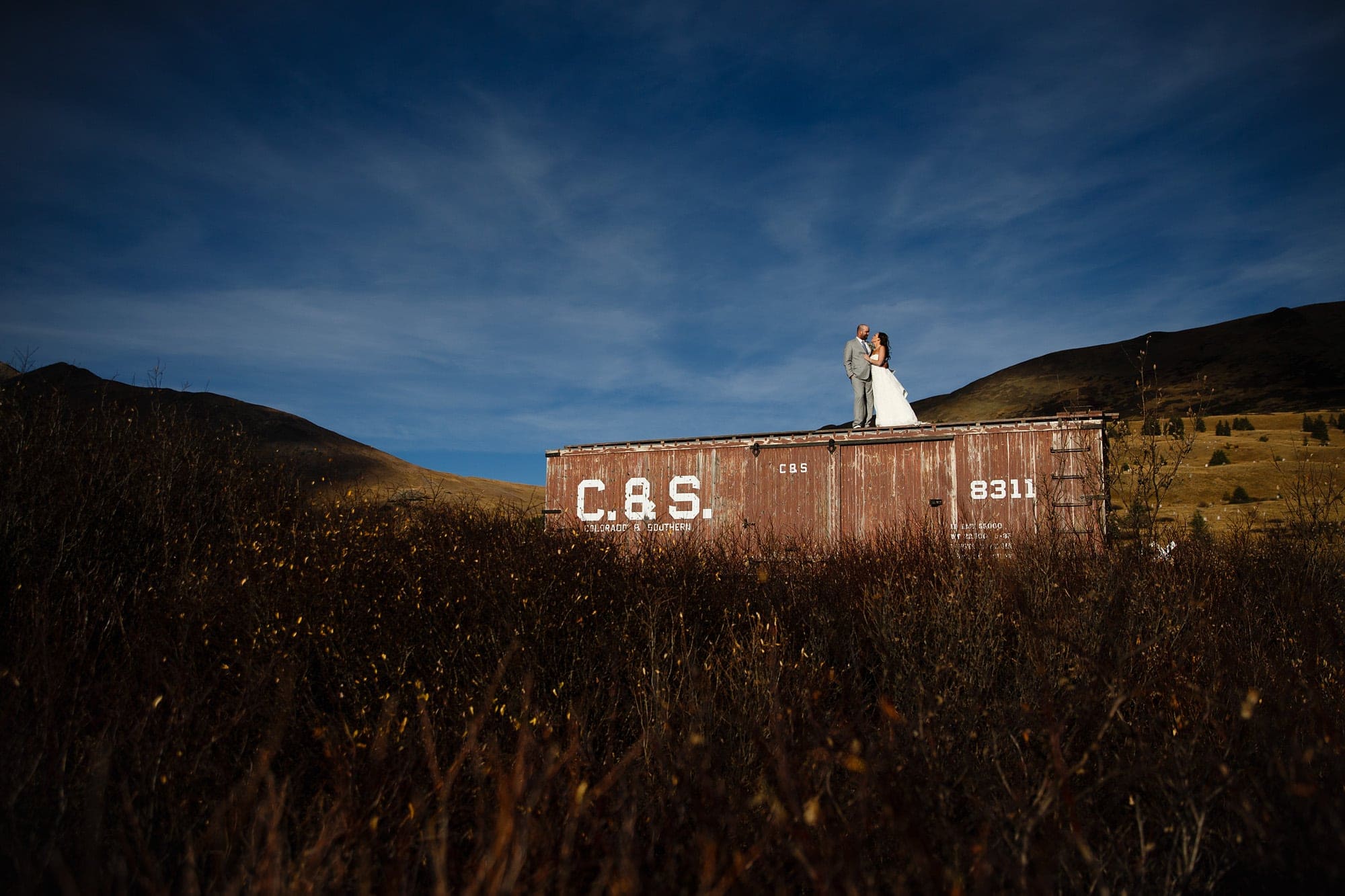 Heidi and Frank pose on a boxcar at the top of Boreas Pass during their wedding near Breckenridge