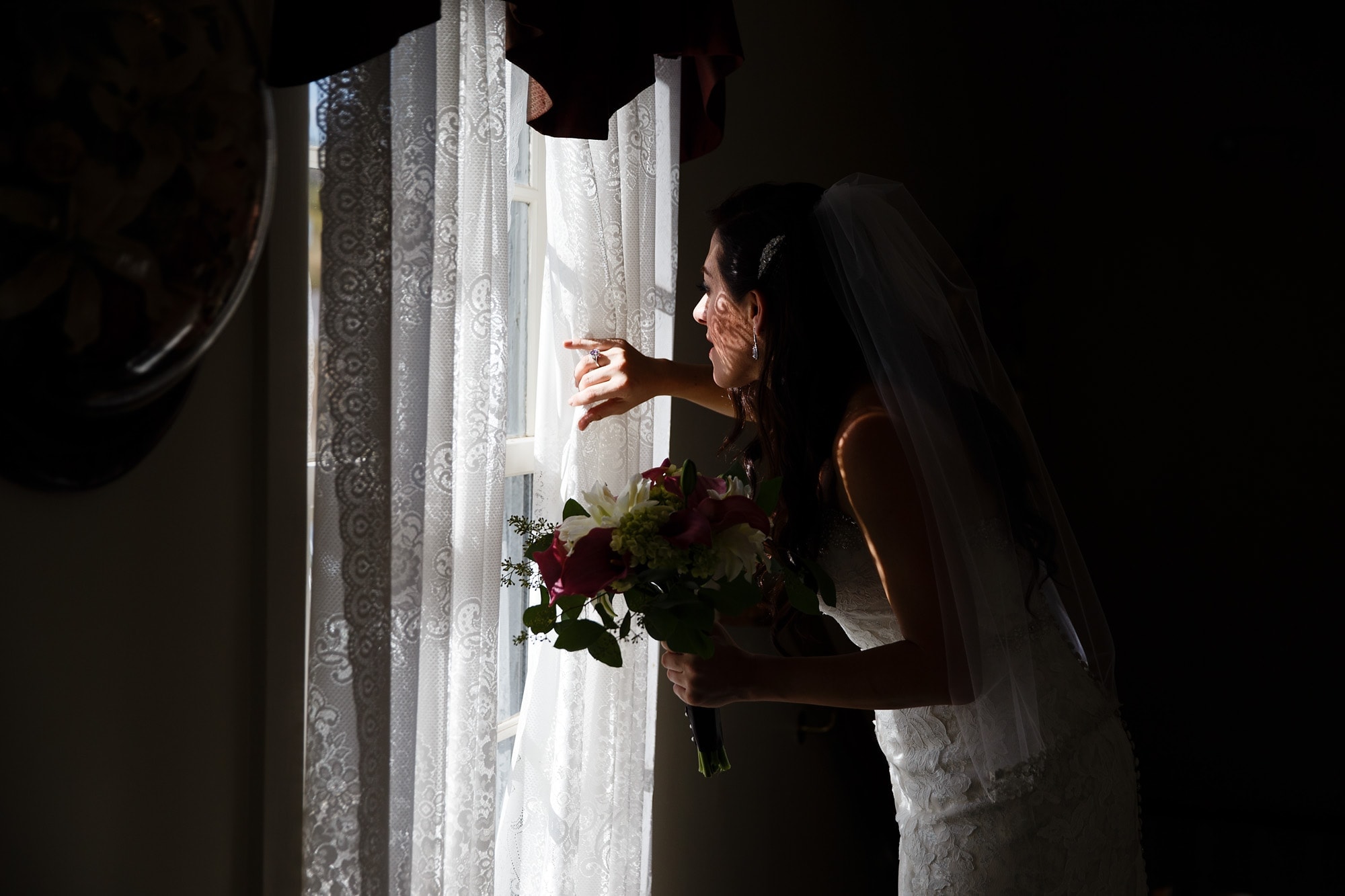 Bride Gina looks out the window before her Willow Ridge Manor wedding