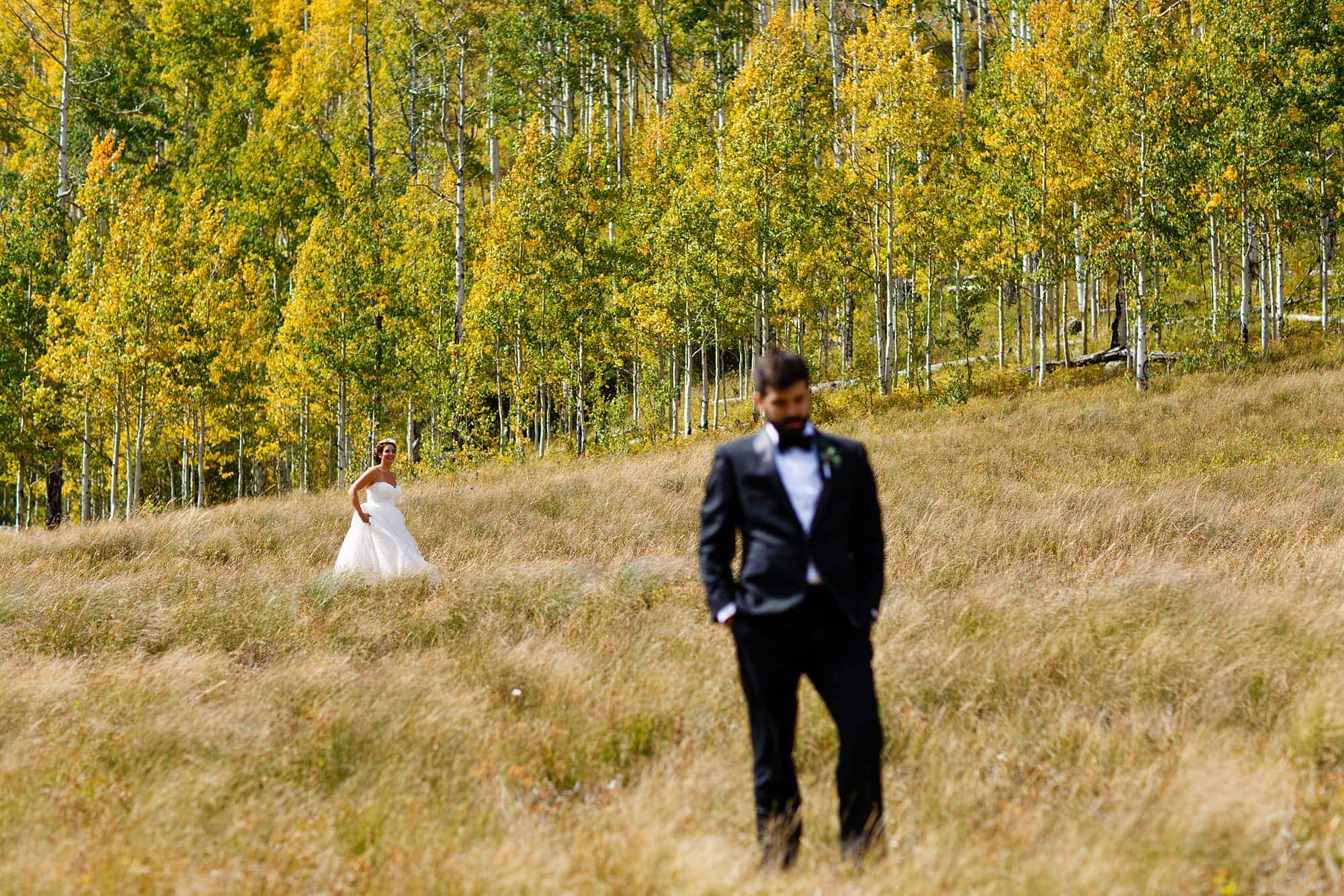 Becky walks towards Brian before their first look as the aspen trees are full of color at Piney River Ranch.