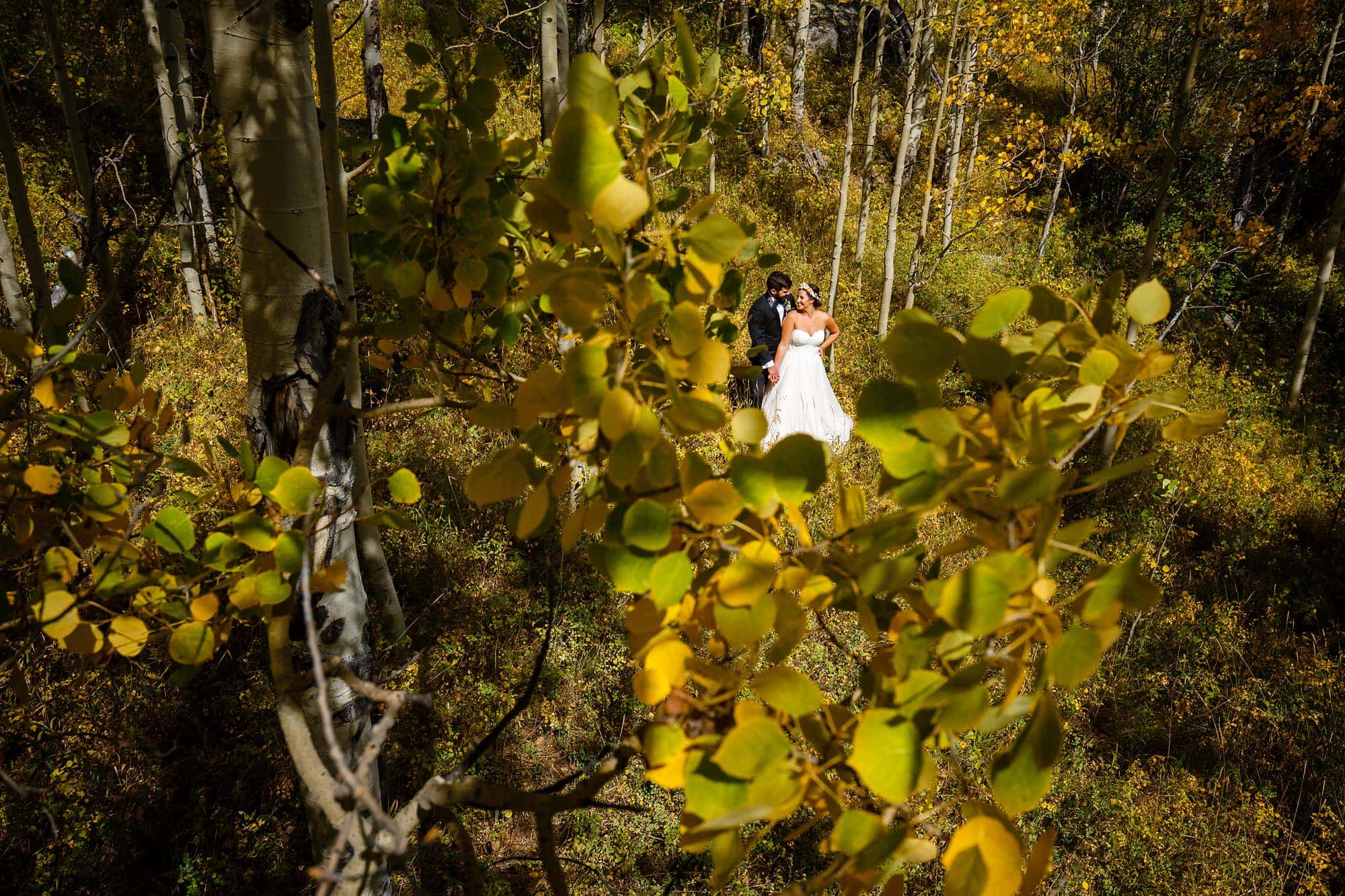 Becky and Brian are surrounded by yellow aspen leaves in September at Piney River Ranch for a portrait.