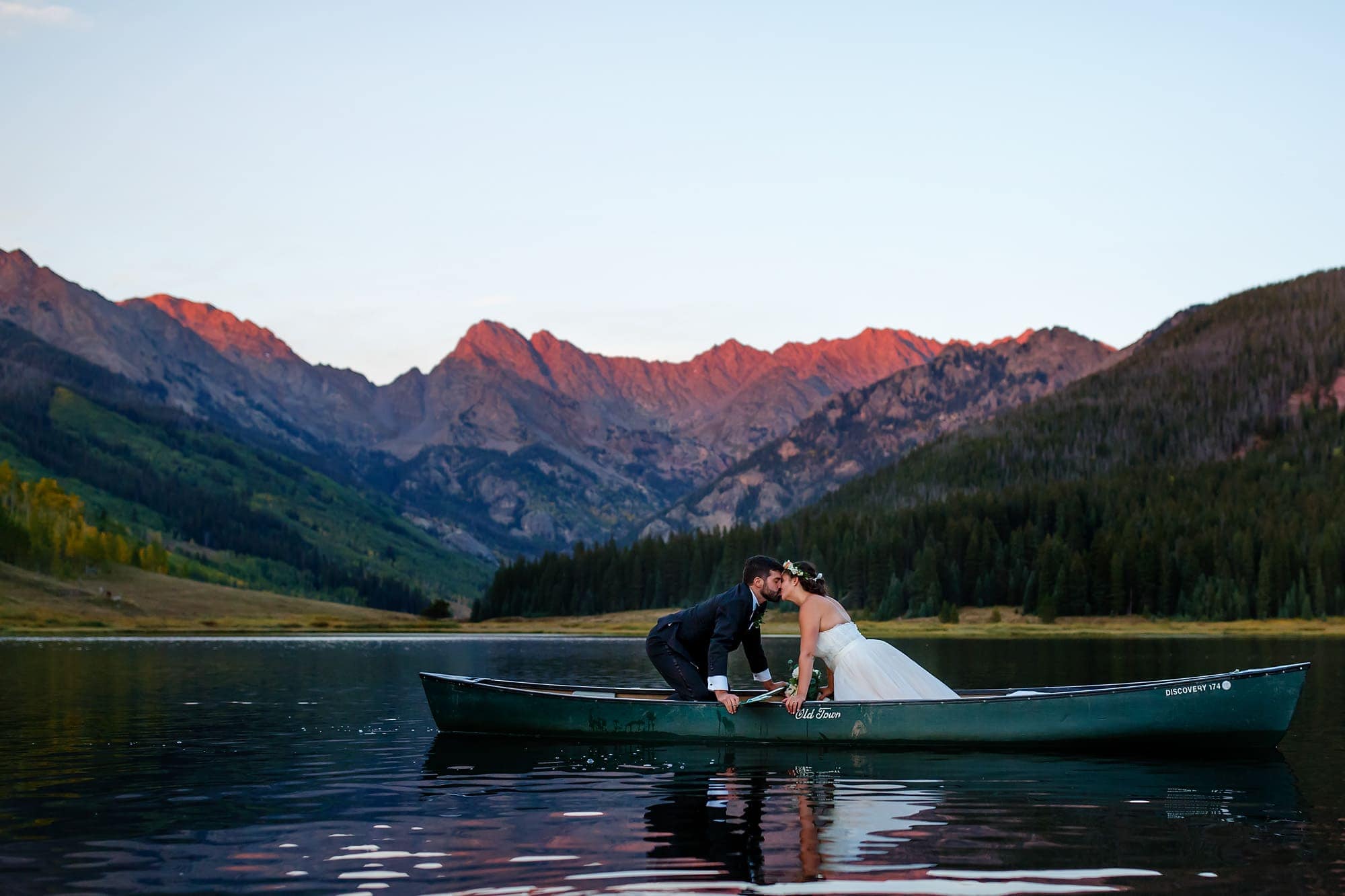 Becky and Brian share a kiss in a canoe on Piney lake as the Gore mountain range are lit by the evening sun during their September wedding.