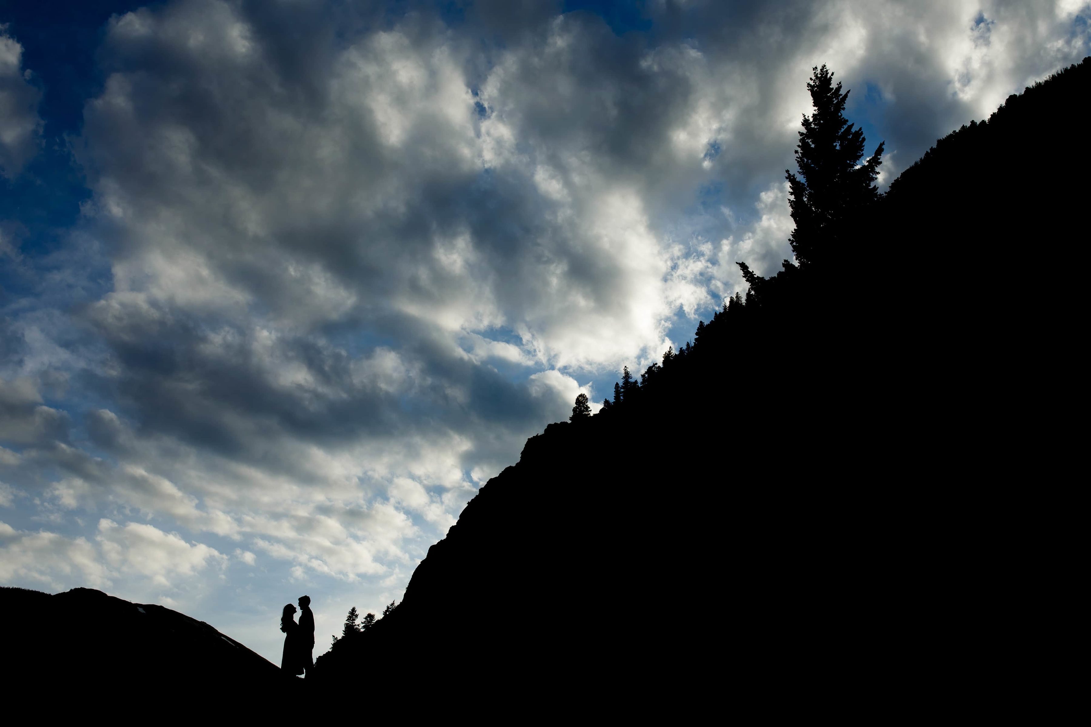 An engaged couple is silhouetted against the sky in Georgetown Colorado