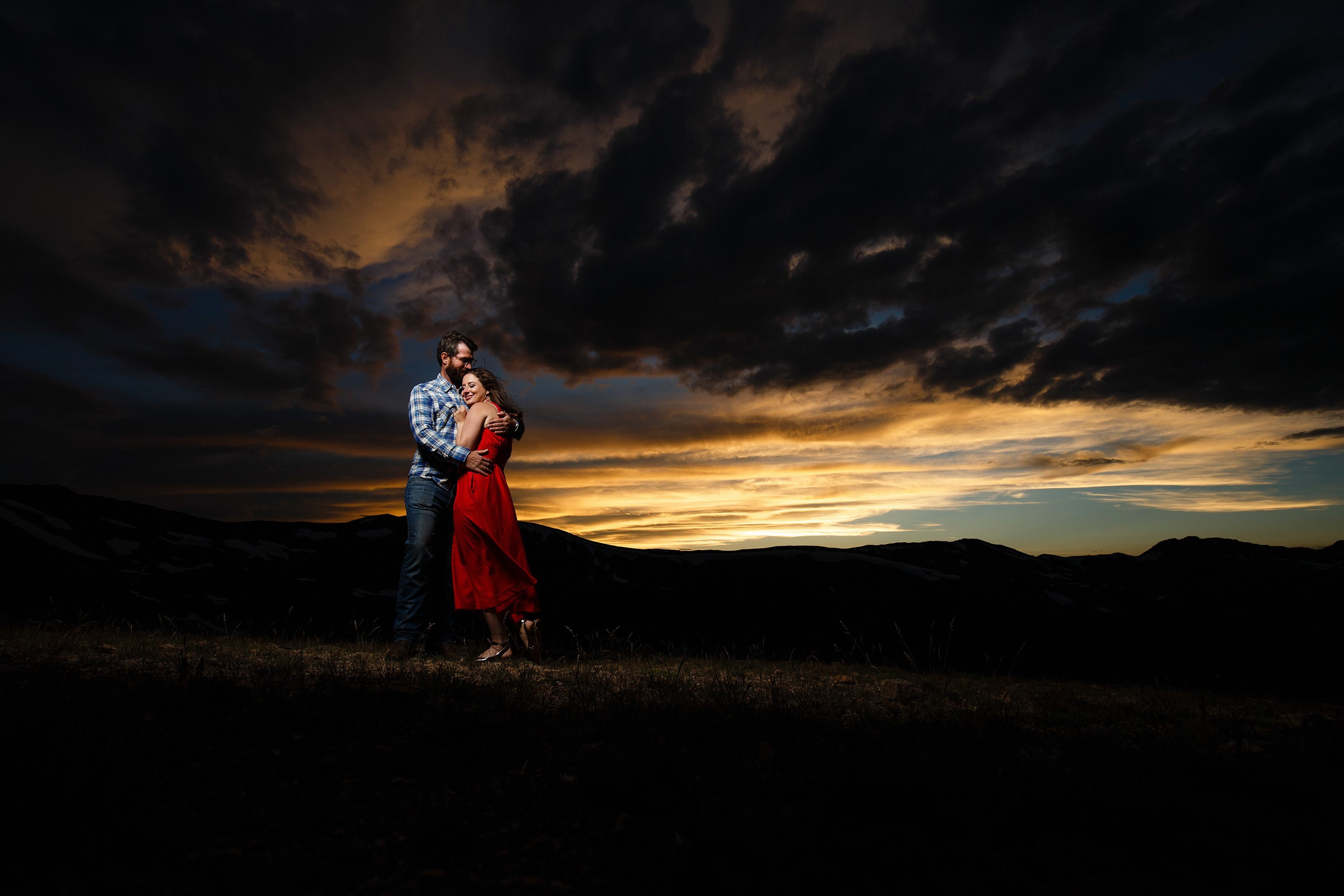 The sun illuminates a beautiful sunset as Mallory and Daniel pose during their summertime engagement photo session atop Loveland Pass near Keystone