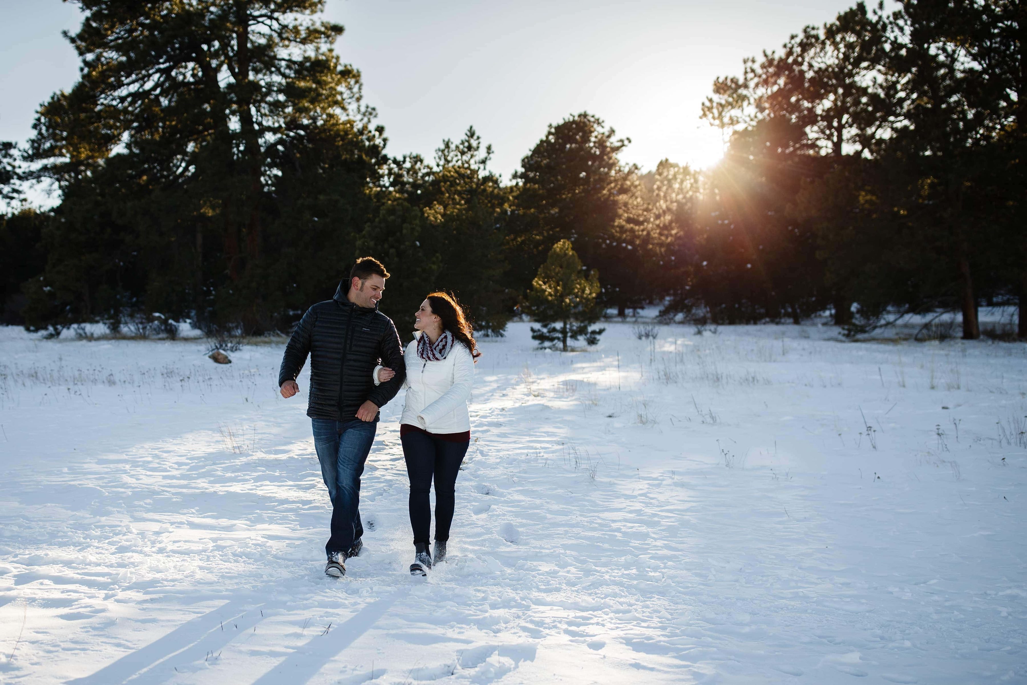 Melissa and Jordan walk through the snow during their winter Elk Meadow Park engagement session near Evergreen, Colorado