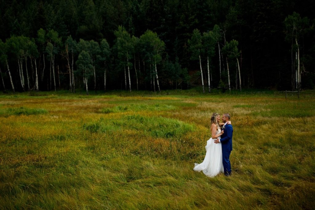 The couple embrace each other in the tall grass at Deer Creek Valley Ranch