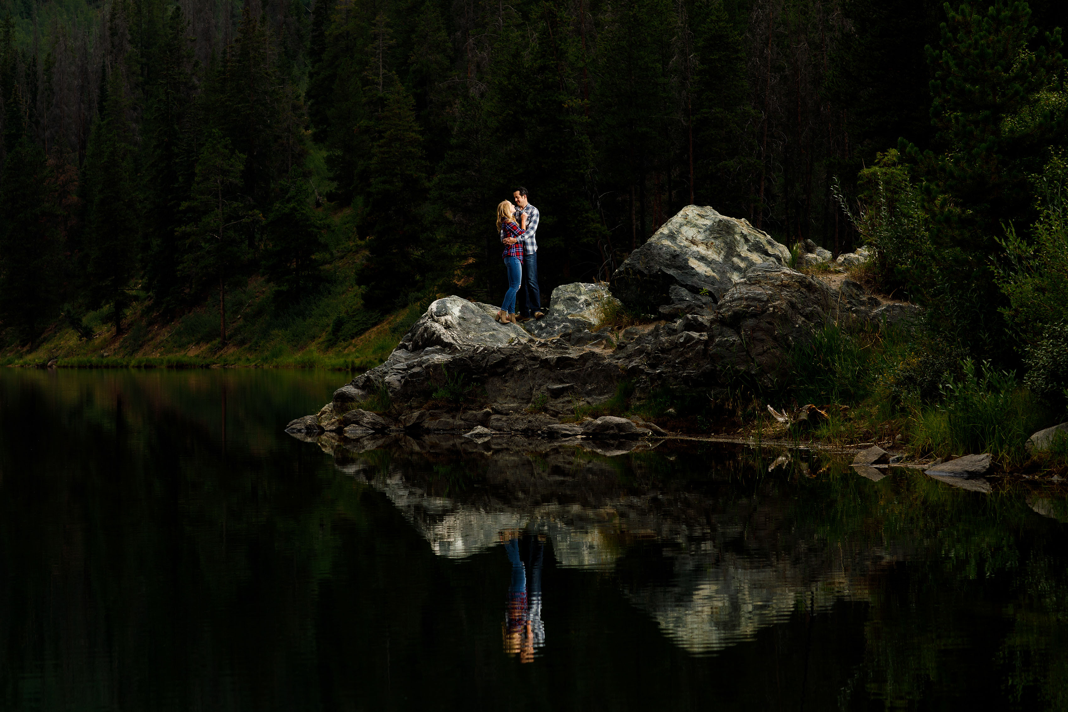 A couple is reflected in the water during their engagement photos at Officer's Gulch near Copper Mountain Colorado
