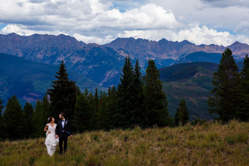 The bride and groom walk together atop Vail mountain on their wedding day