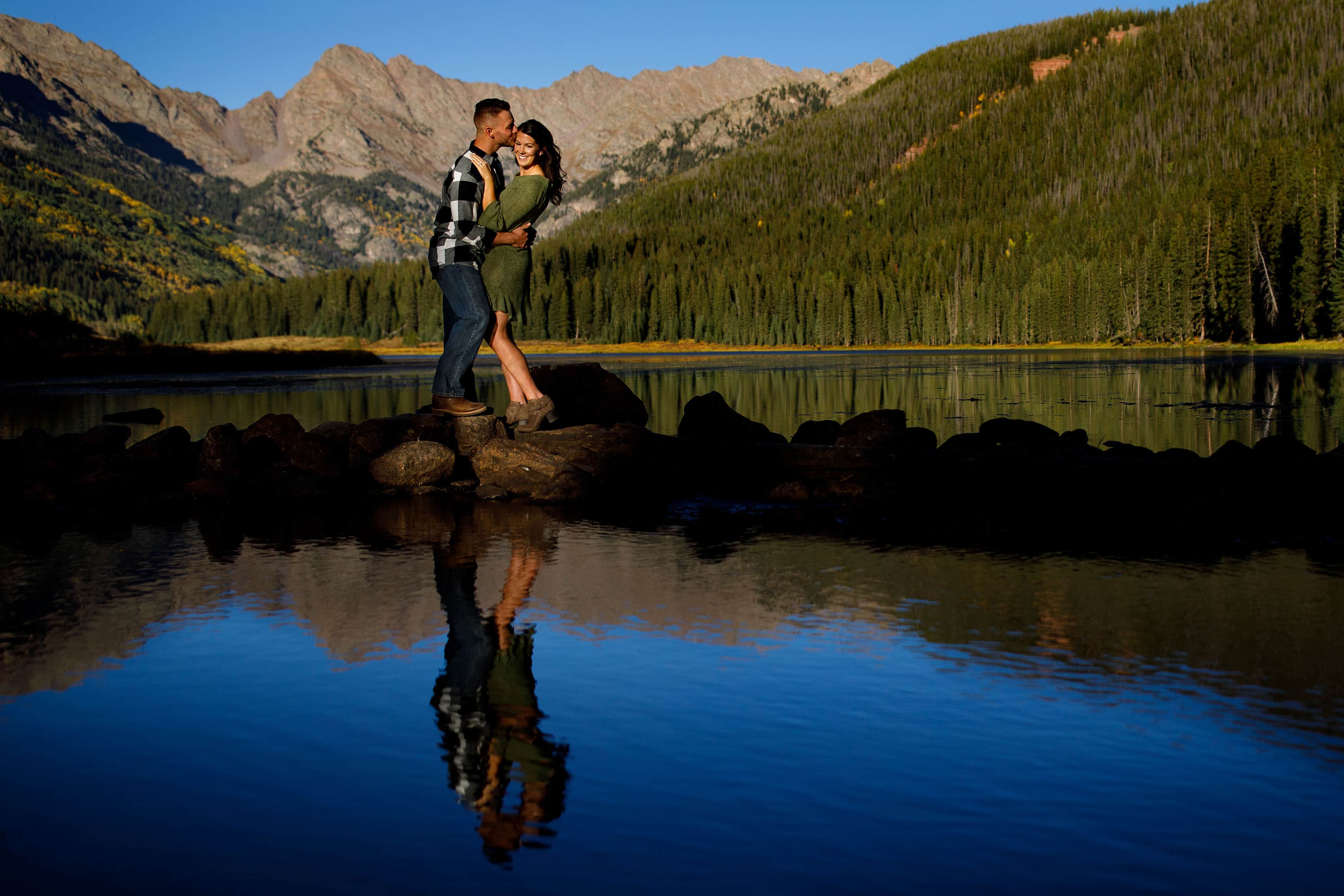 Brendan kisses Caroline near the water edge at Piney River Ranch during their engagement session in Vail
