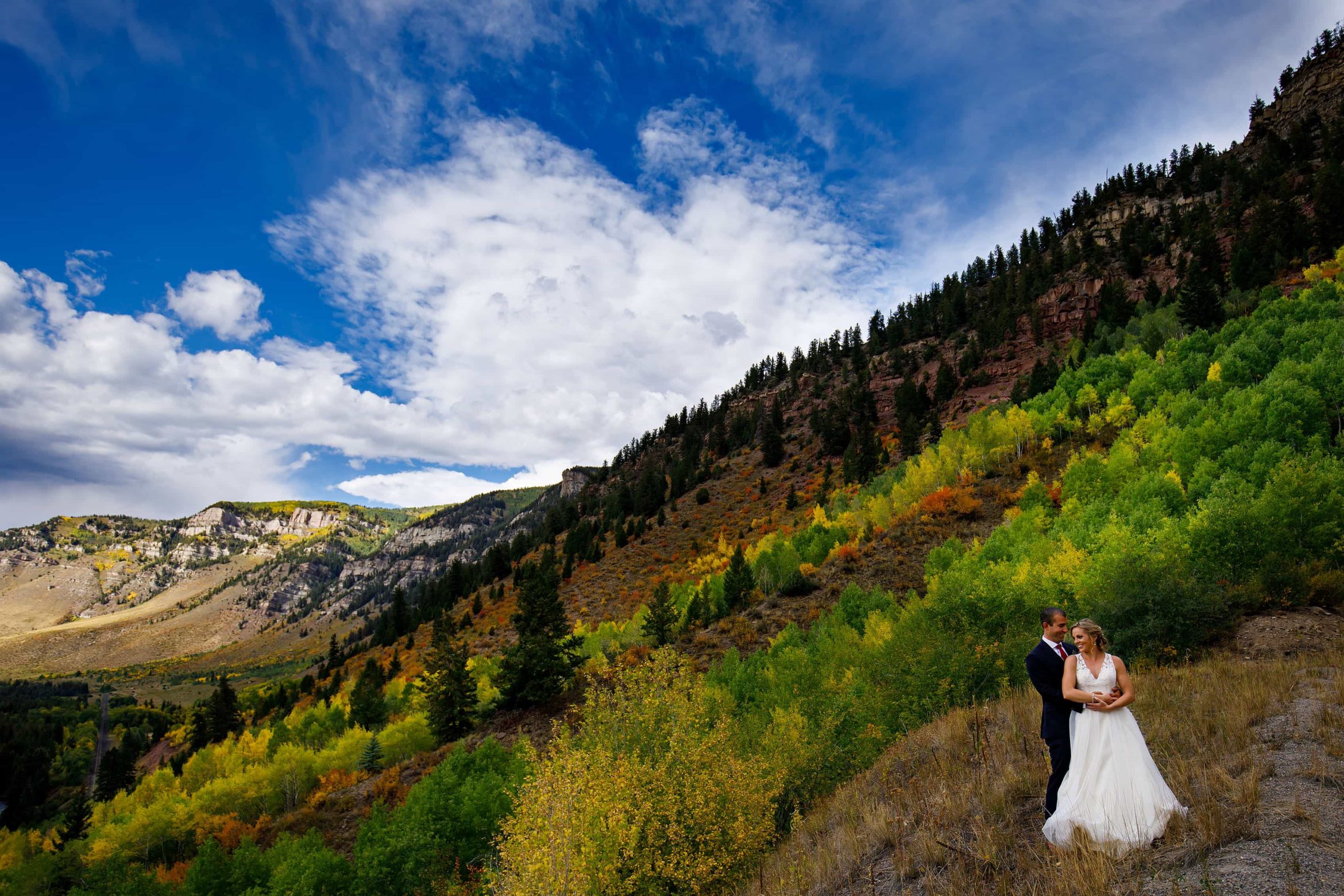 A couple embrace along the 10th mountain division memorial highway near a grove of colorful aspen trees in the fall during their Camp Hale wedding