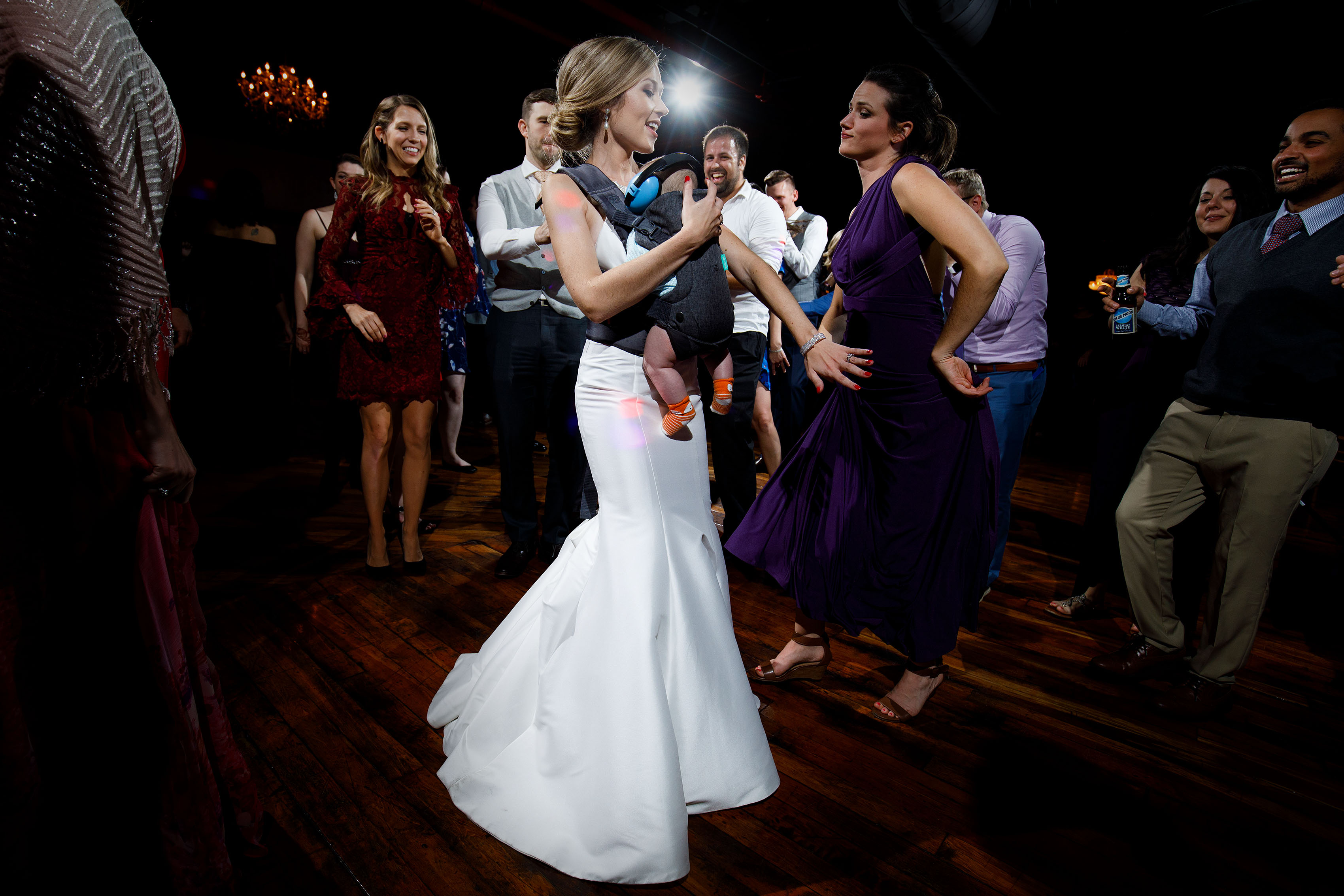 The bride dances with a newborn during her Madison at the Mill wedding