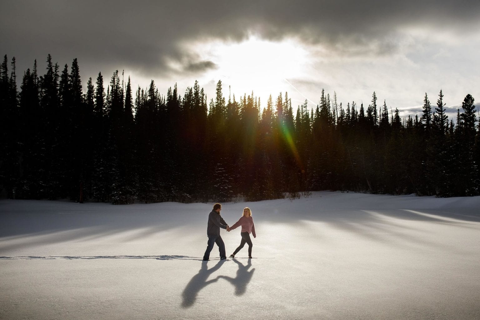Meaghan and Aaron walk together on the snow covered ice during their winter Brainard Lake Engagement in Colorado