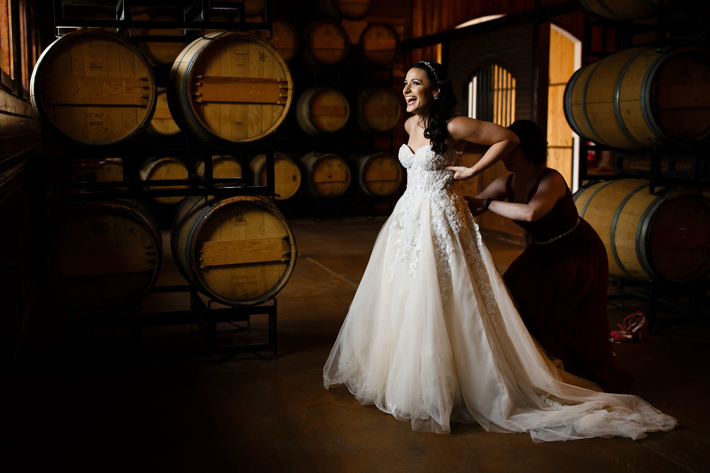 Bride puts on her dress in the barrell room at Crooked Willow Farms before her wedding