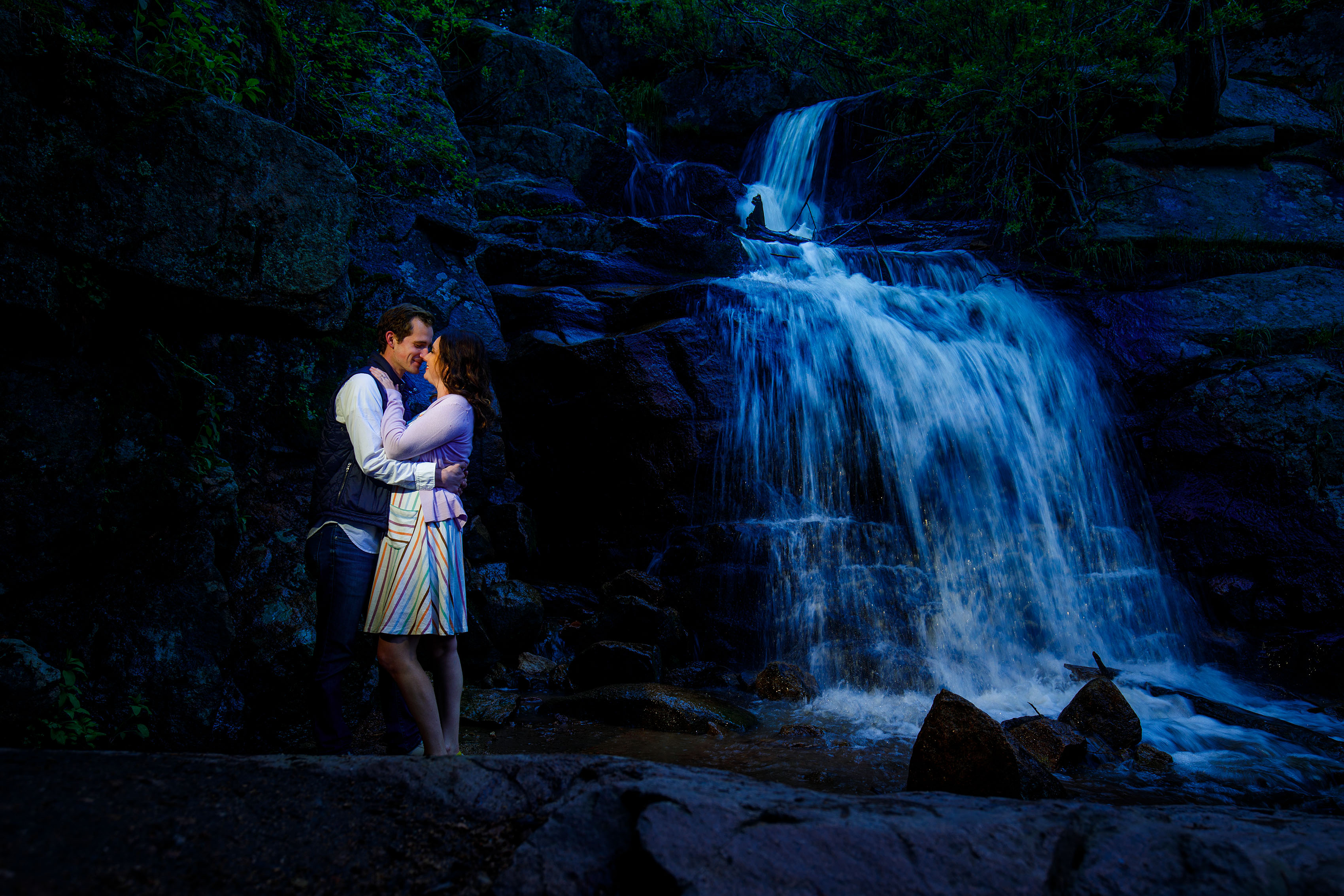 A couple embrace at Maxwell Falls in Evergreen during their engagement photo session