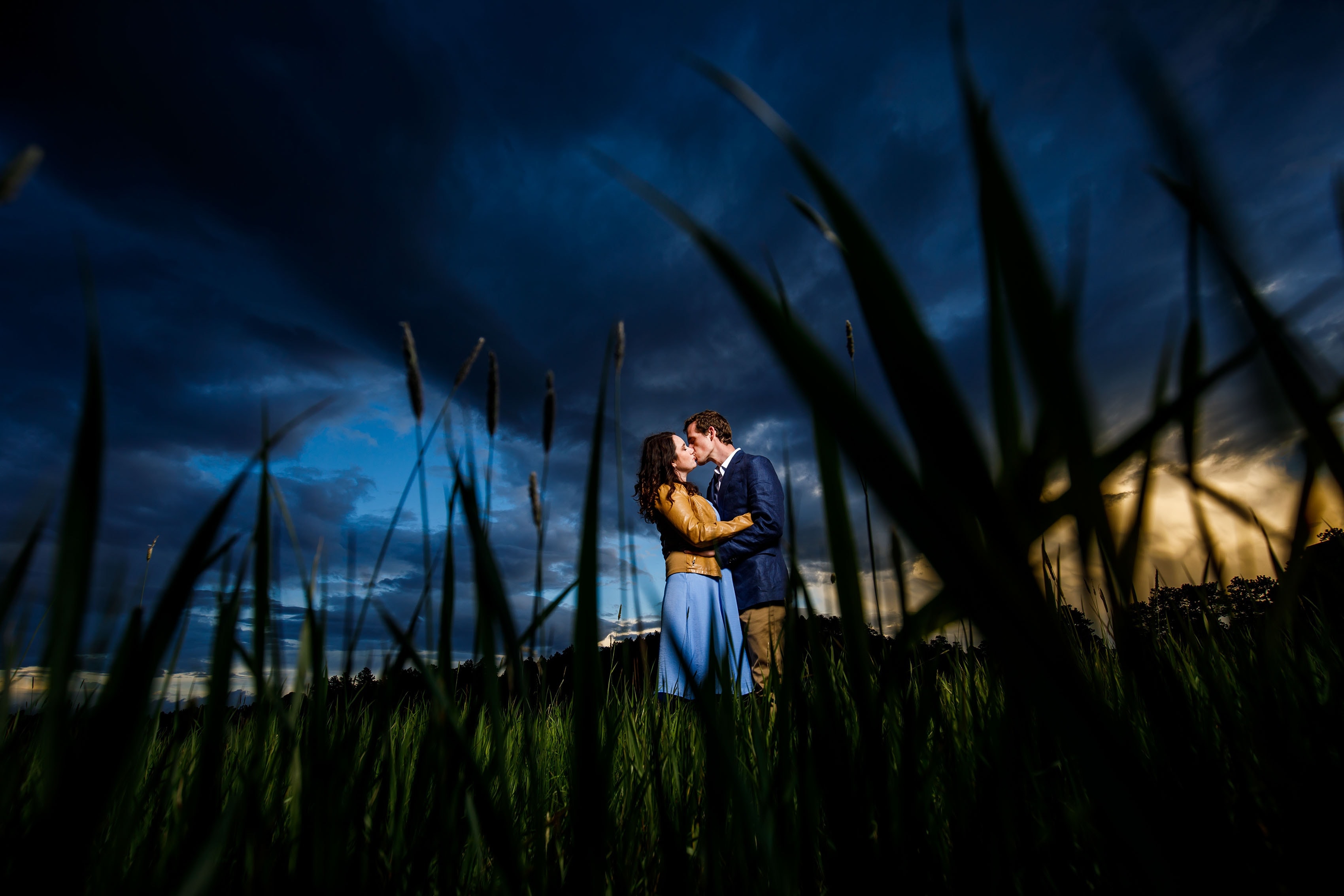 A couple kiss in the meadow at sunset during their Alderfer Three Sisters Park engagement