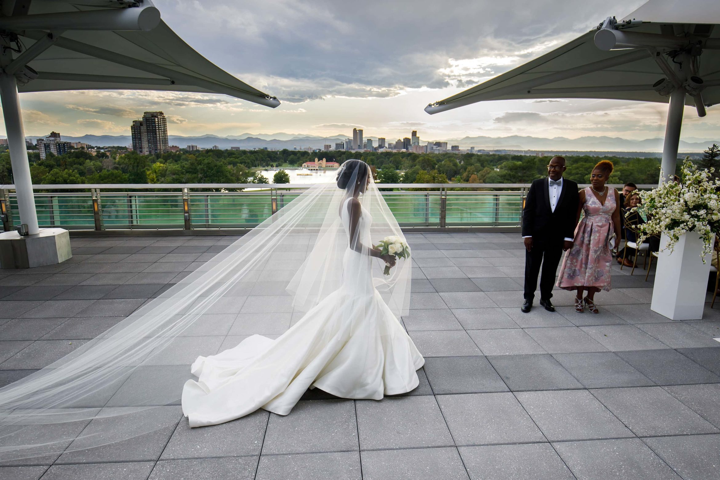 The bride walks down the aisle on the rooftop at the Denver Museum of Nature and Science during her wedding