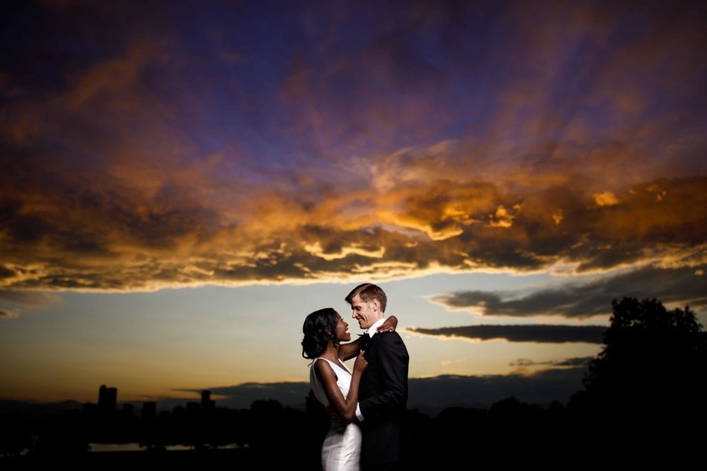 A couple pose together under a Denver sunset during their wedding day
