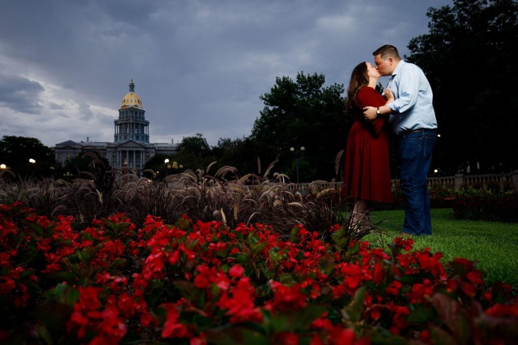 Matt and Katie kiss in Civic Center Park with the Colorado State Capitol in the background