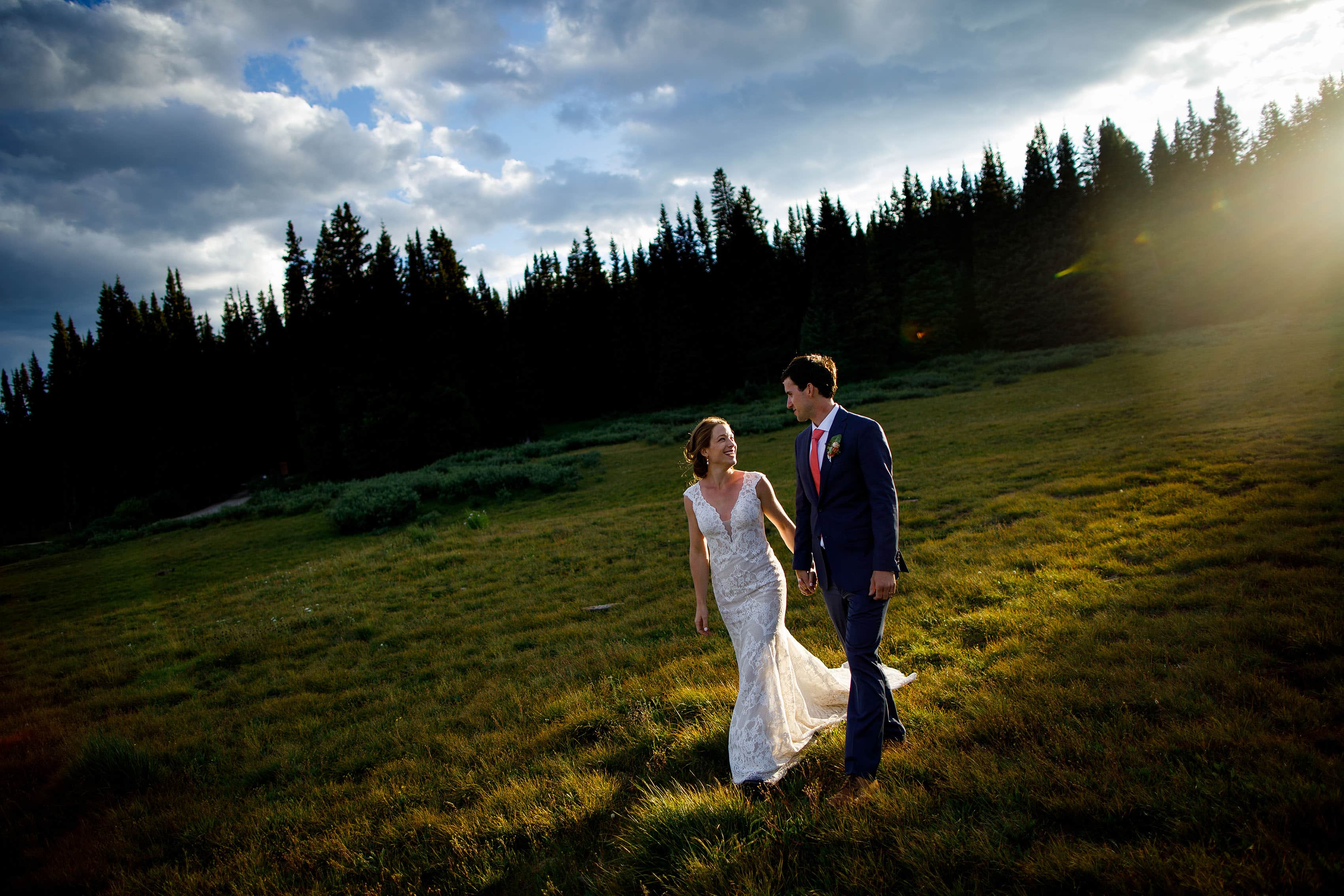 The sun flares over the ridge as Carissa and Kyle walk together at Shrine Pass