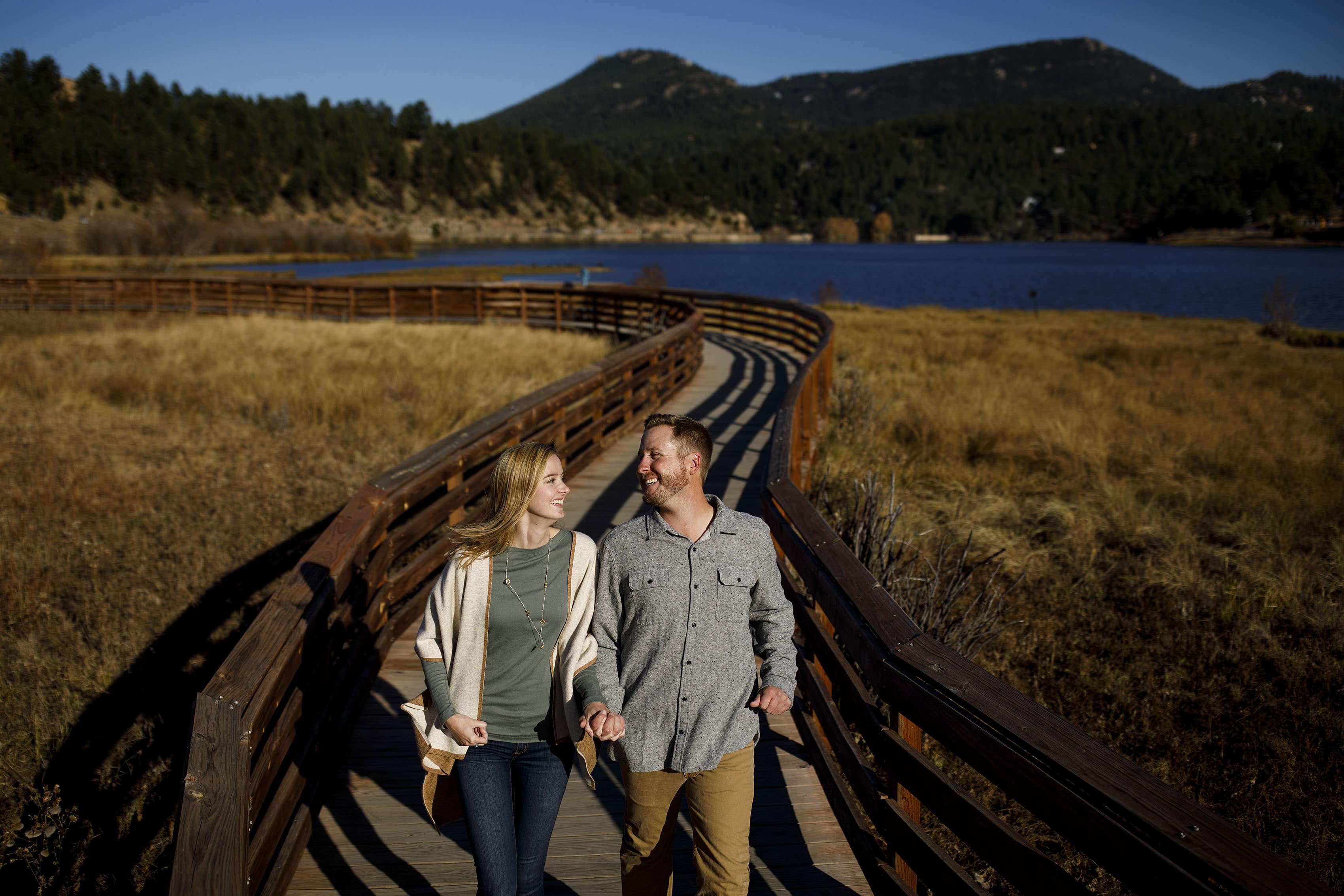 Jennifer and Stefan laugh together on the wooden path at Evergreen Lake during a fall day