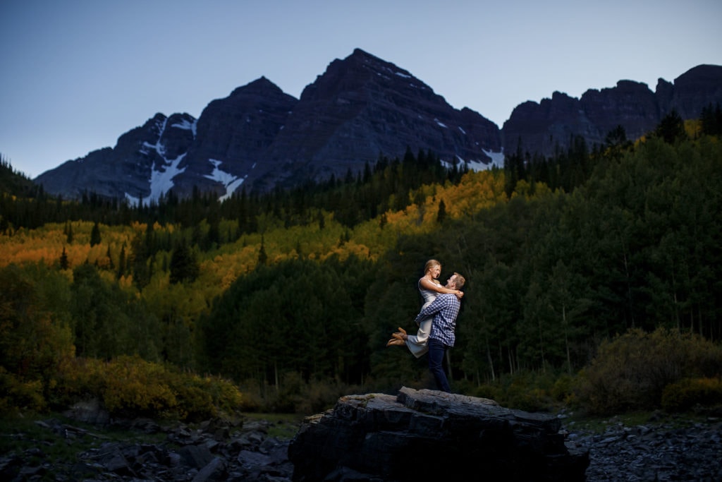 A couple poses at the Maroon Bells near a grove of yellow aspen trees during their fall engagement session in Aspen, Colorado.