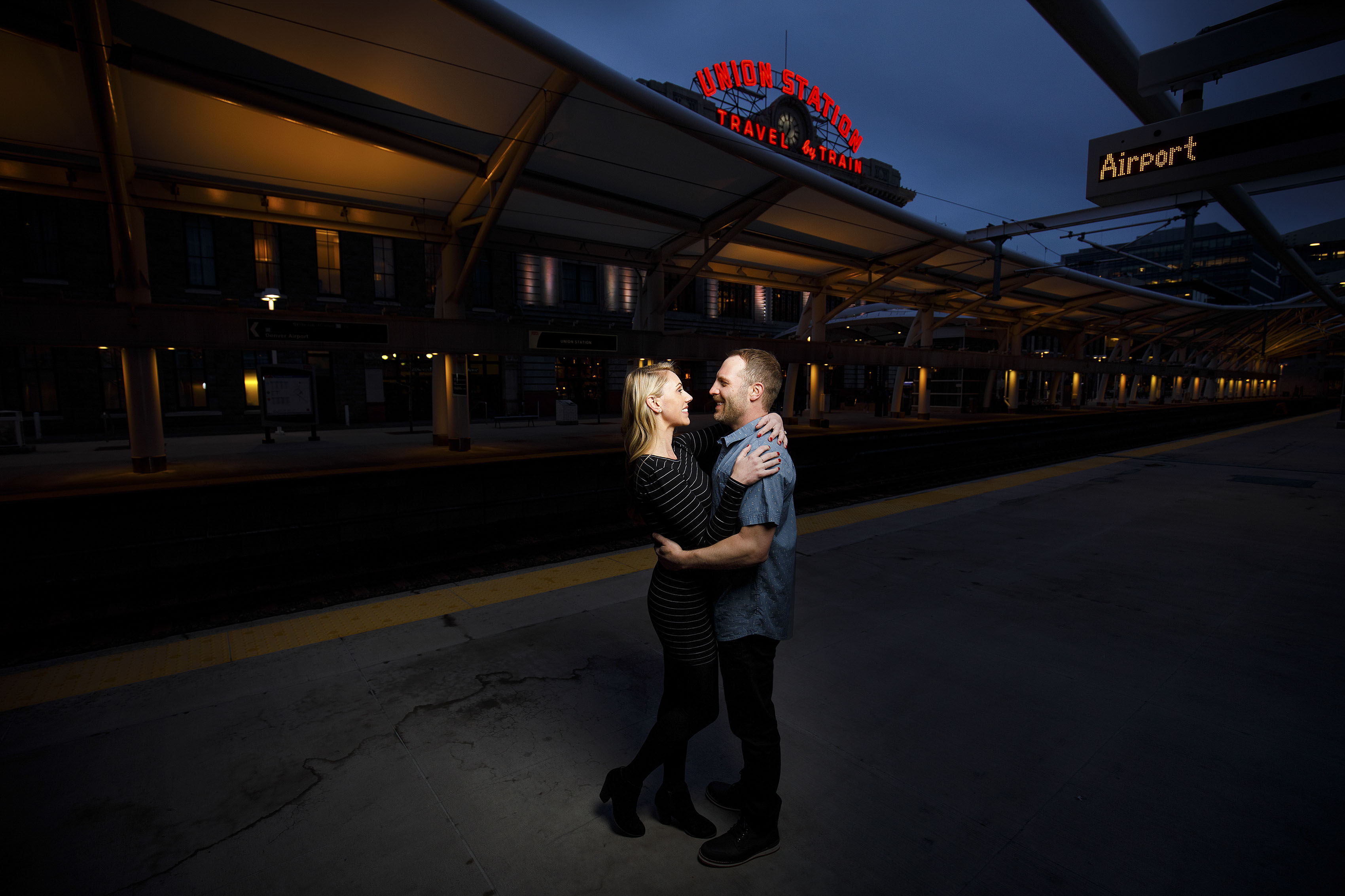 A couple poses on the train platform at Denver's Union Station during their engagement photos