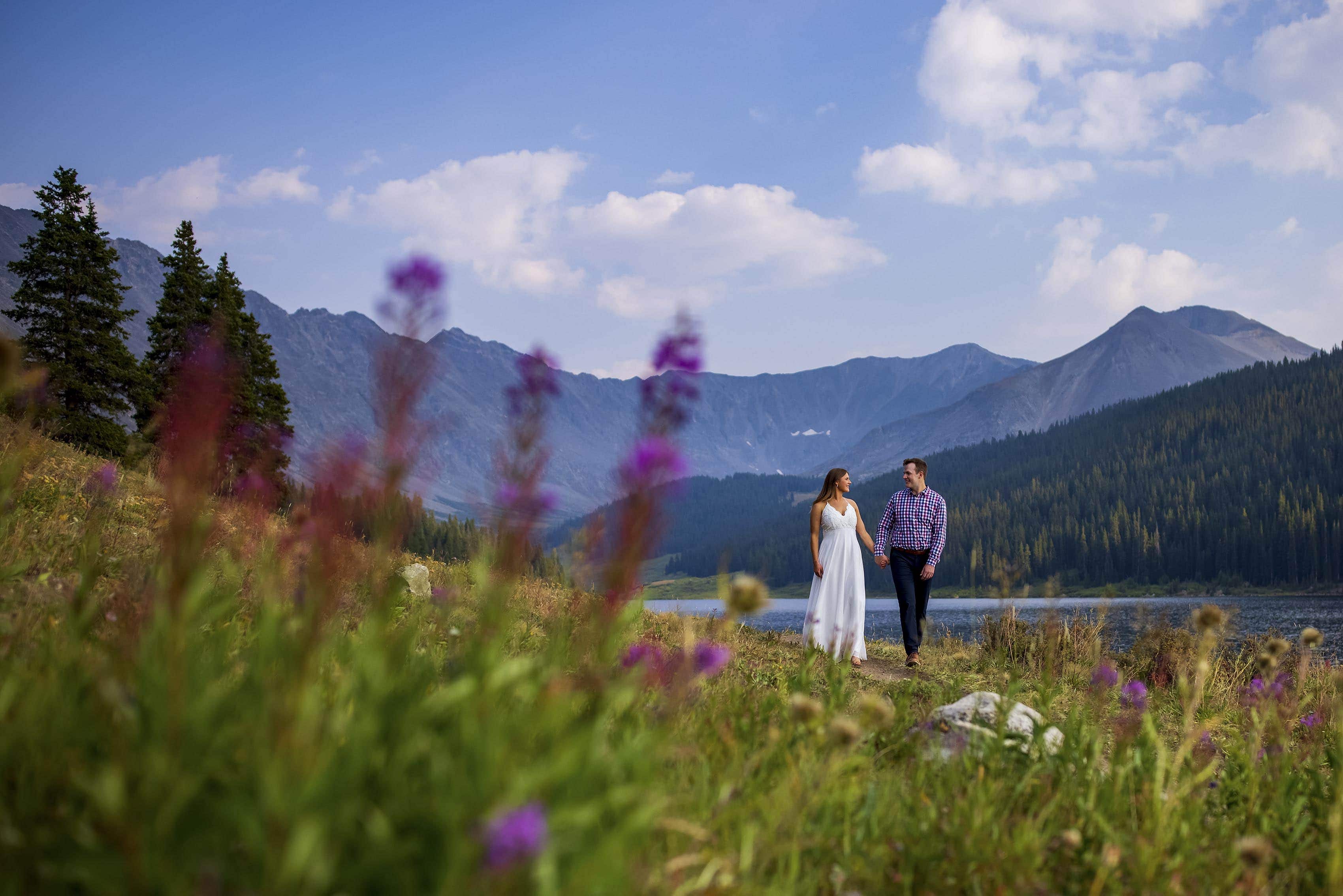 Wildflowers in bloom as a bride and groom walk together at Clinton Gulch Dam Reservoir