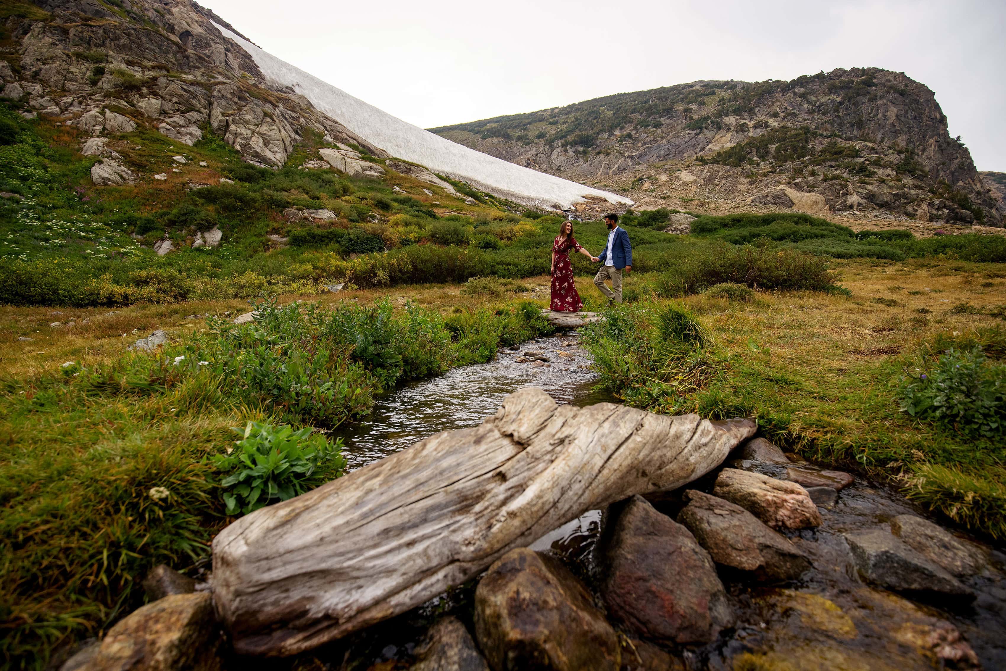 A couple walk across the stream at St. Mary's Glacier