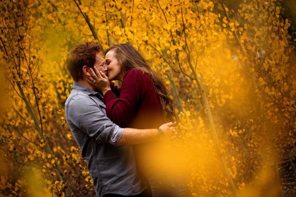 Casey and Darren share a kiss in a grove of aspen trees during their fall engagement session