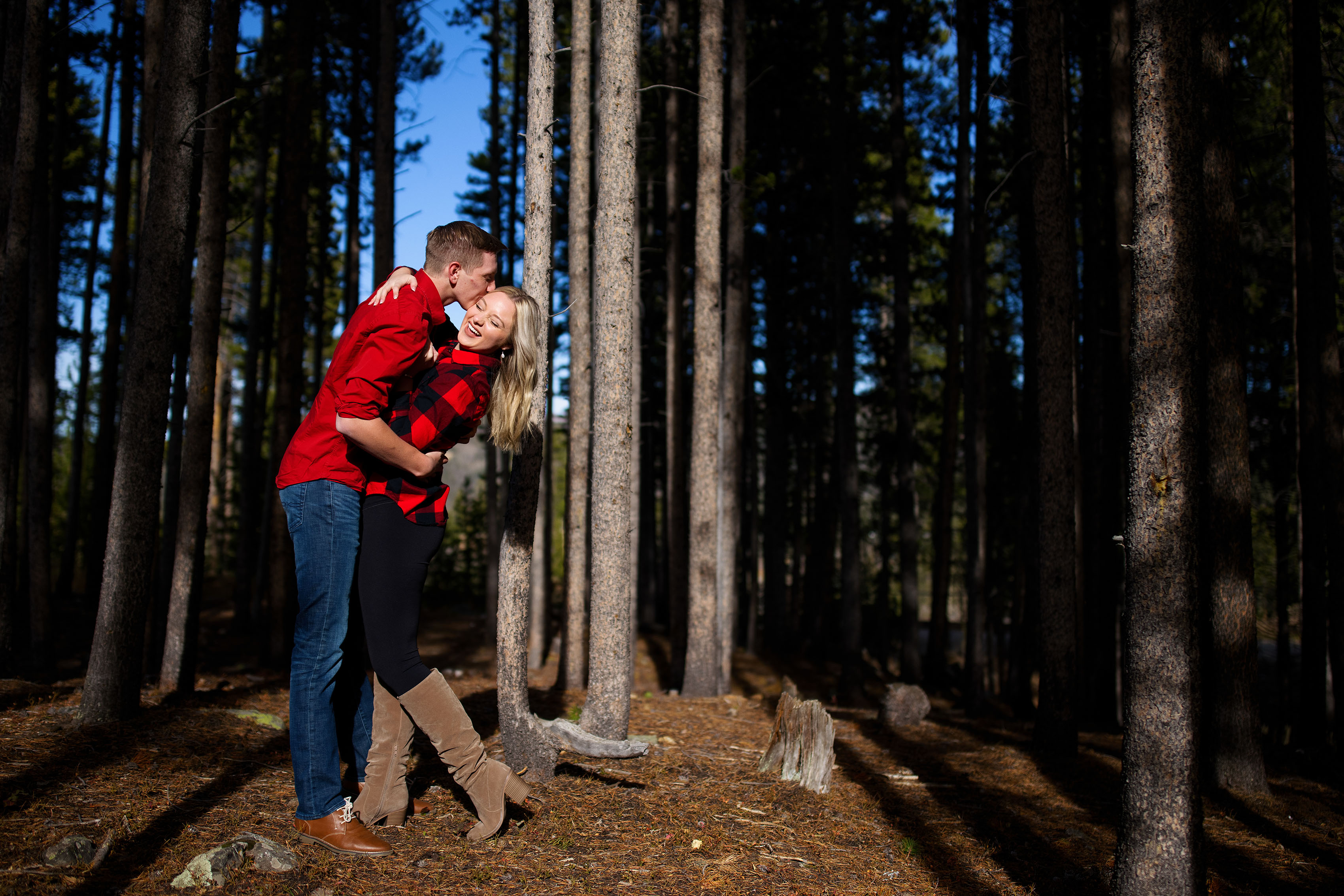 Joseph kisses Chloe in a grove of pine trees at Sawmill Reservoir