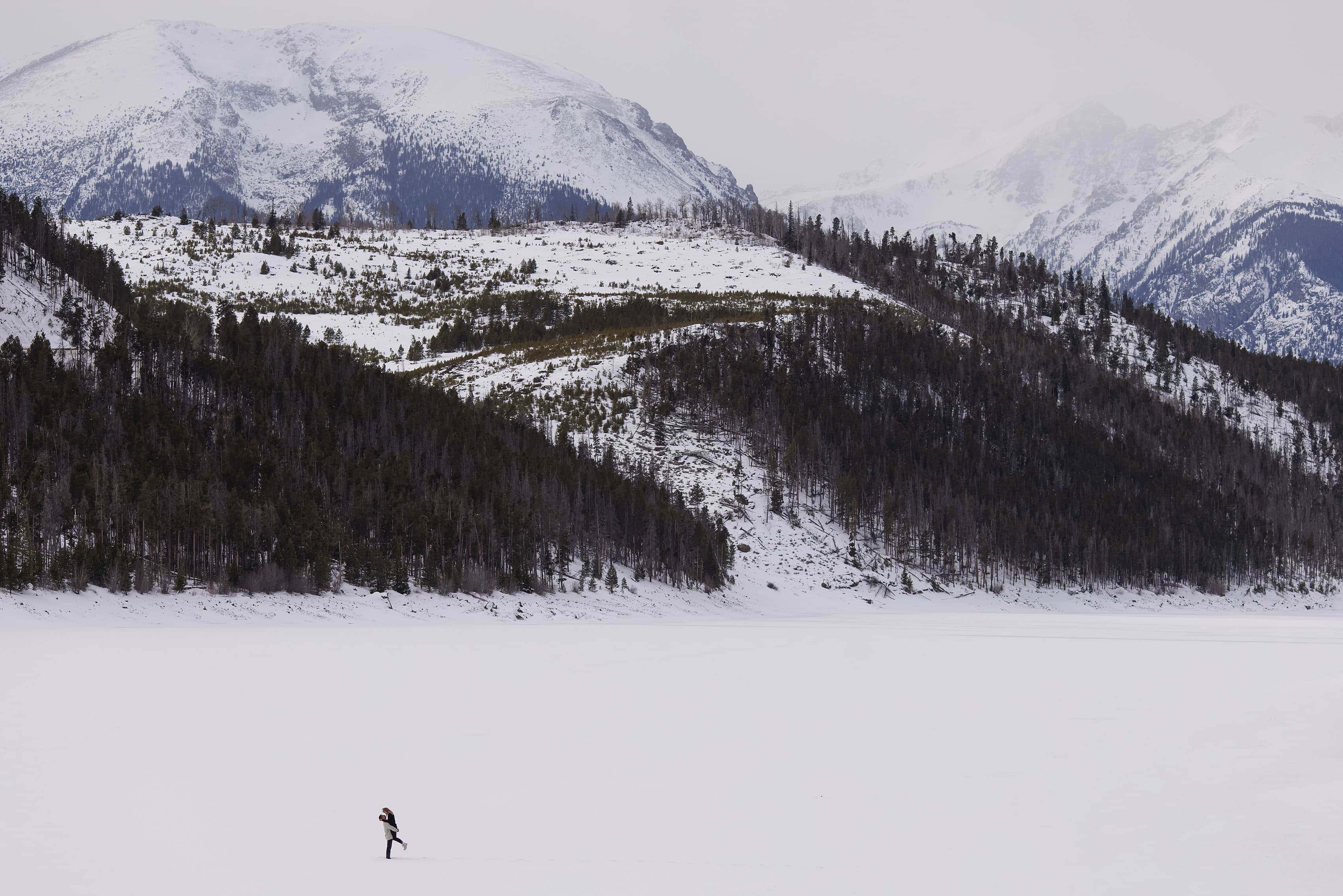 A couple embraces on Lake Dillon in the snow near the Tenmile Range