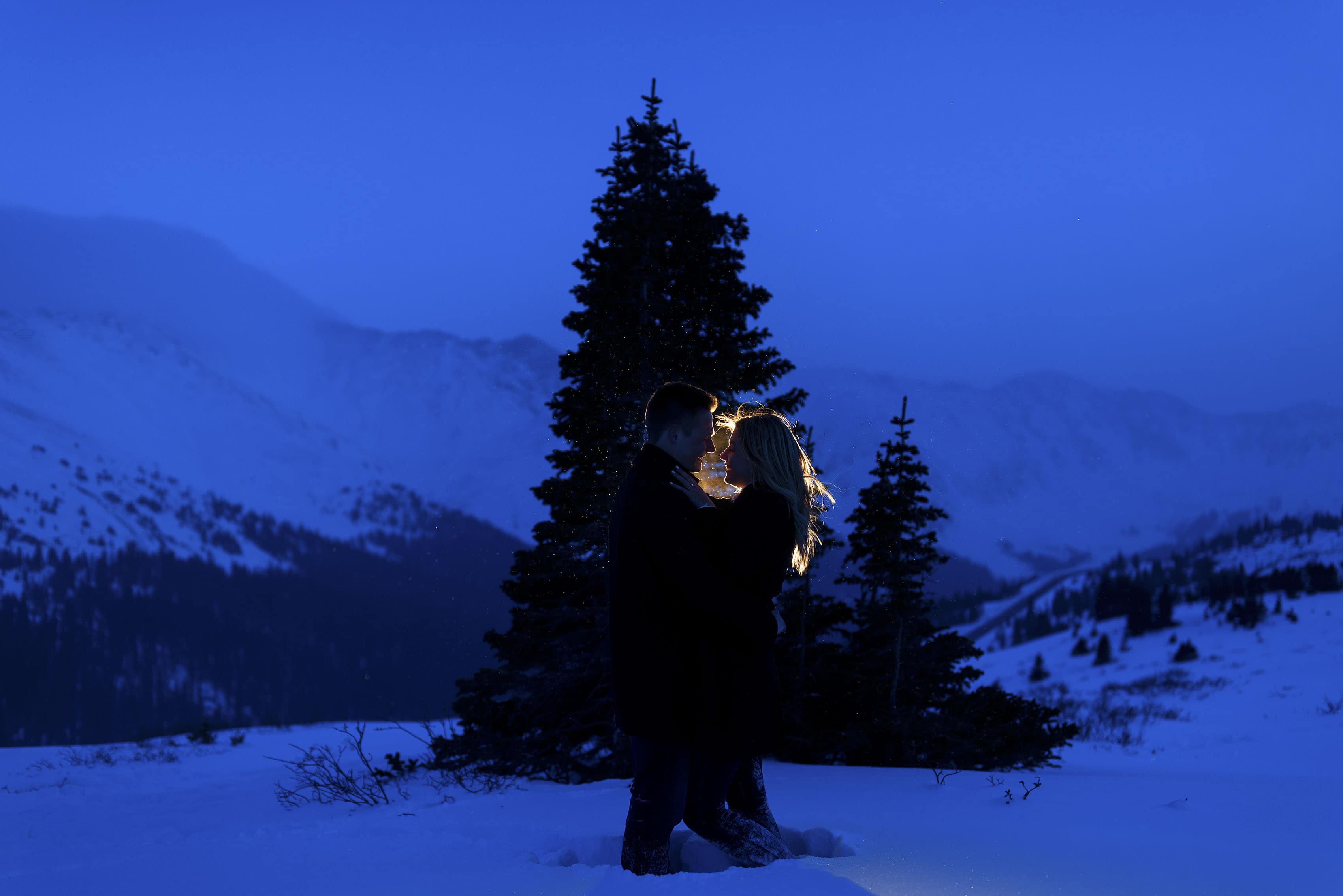 A couple is illuminated on Loveland Pass during their engagement photos