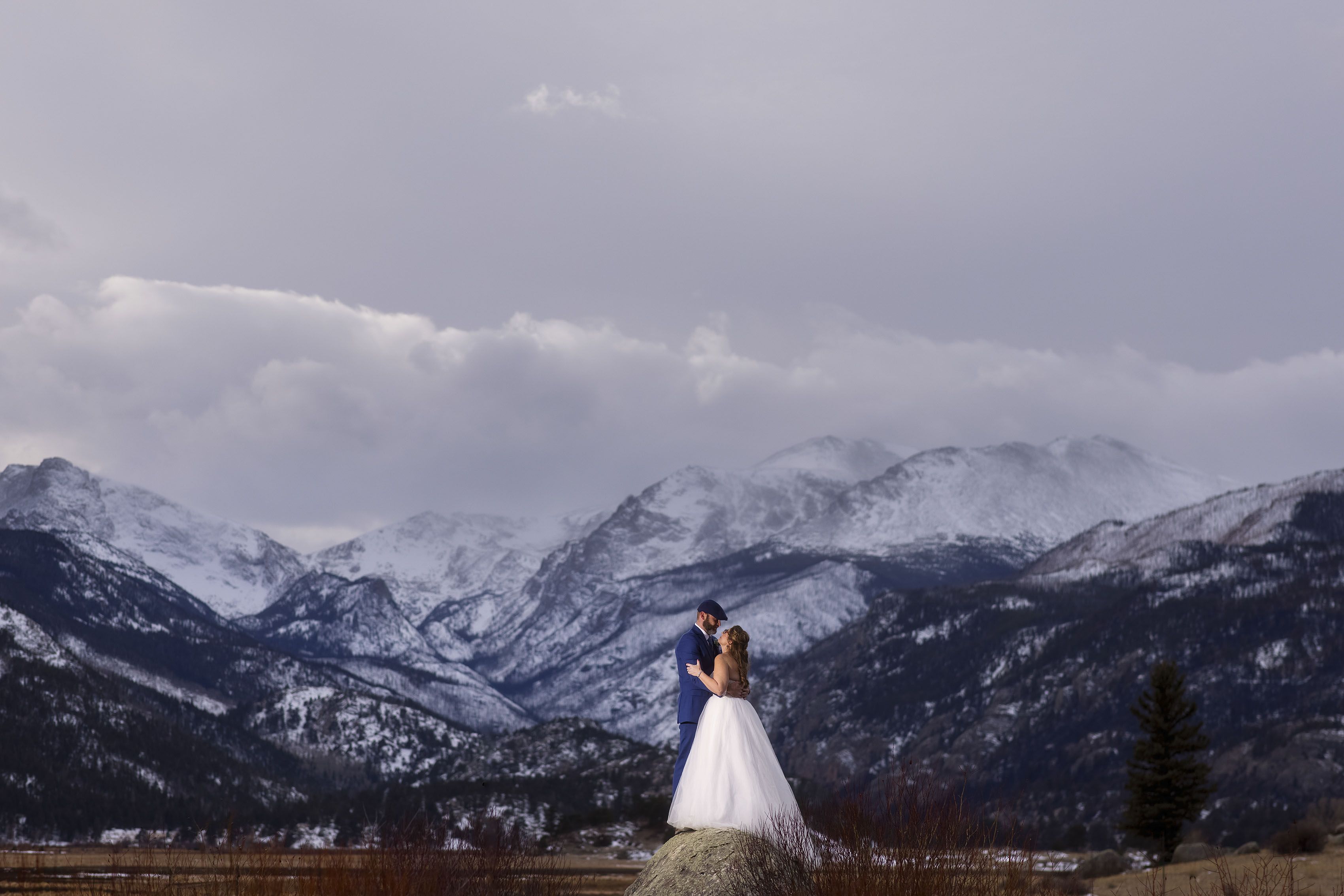 A couple share a moment together on a rock in Moraine Park in the valley at Rocky Mountain National Park during their winter elopement