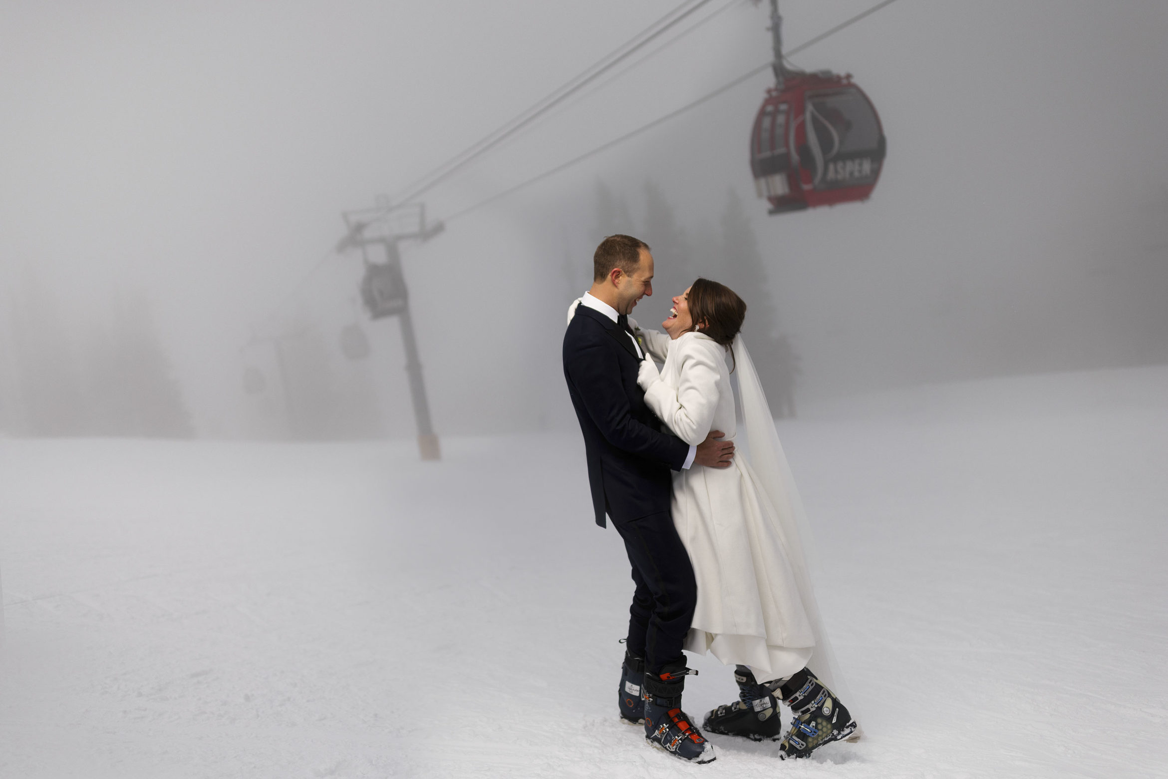 The bride and groom share a laugh while posing for a portrait as the fog rolls in on Aspen mountain following their micro wedding ceremony