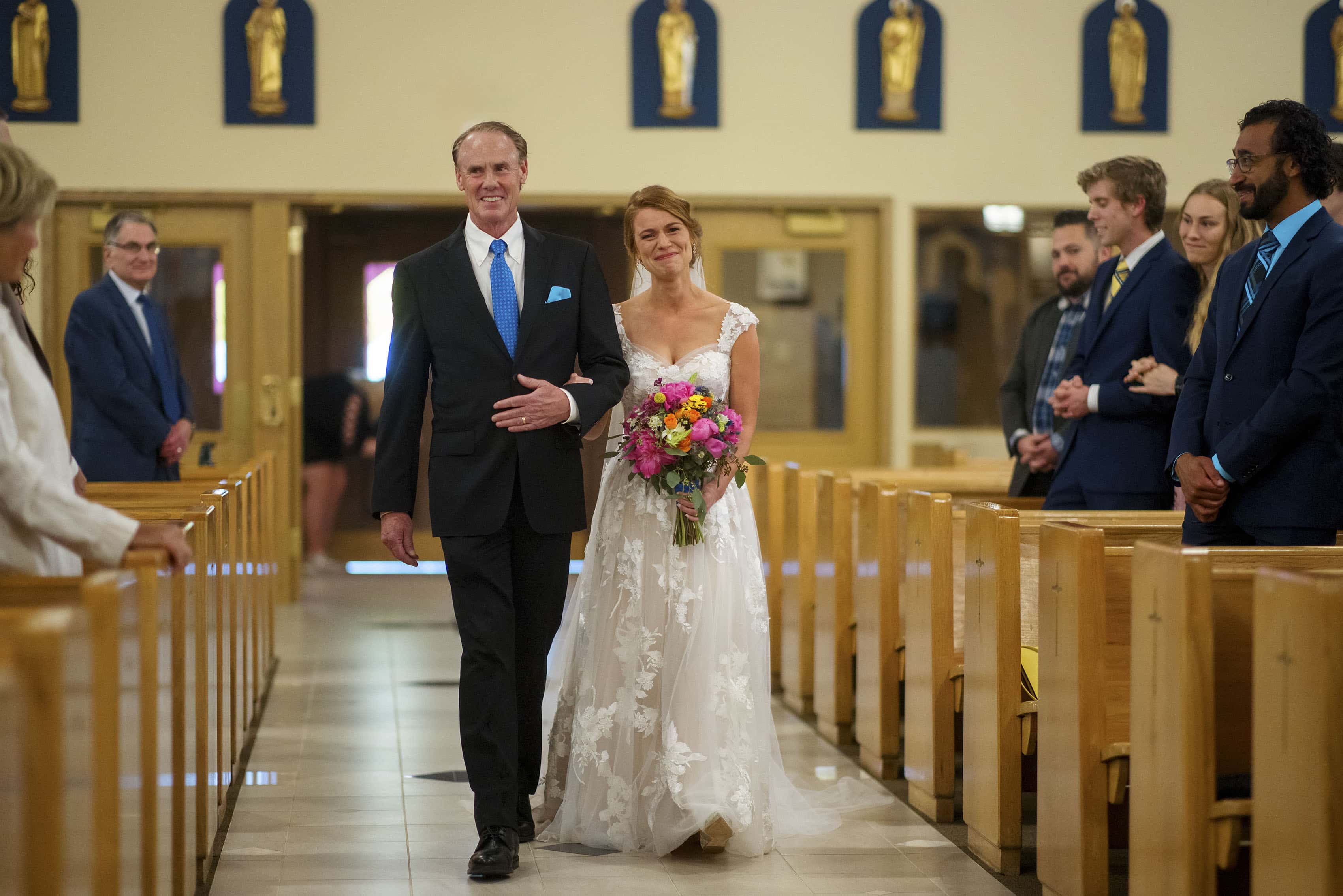 The bride walks down the aisle with her father at Holy Name Catholic Church