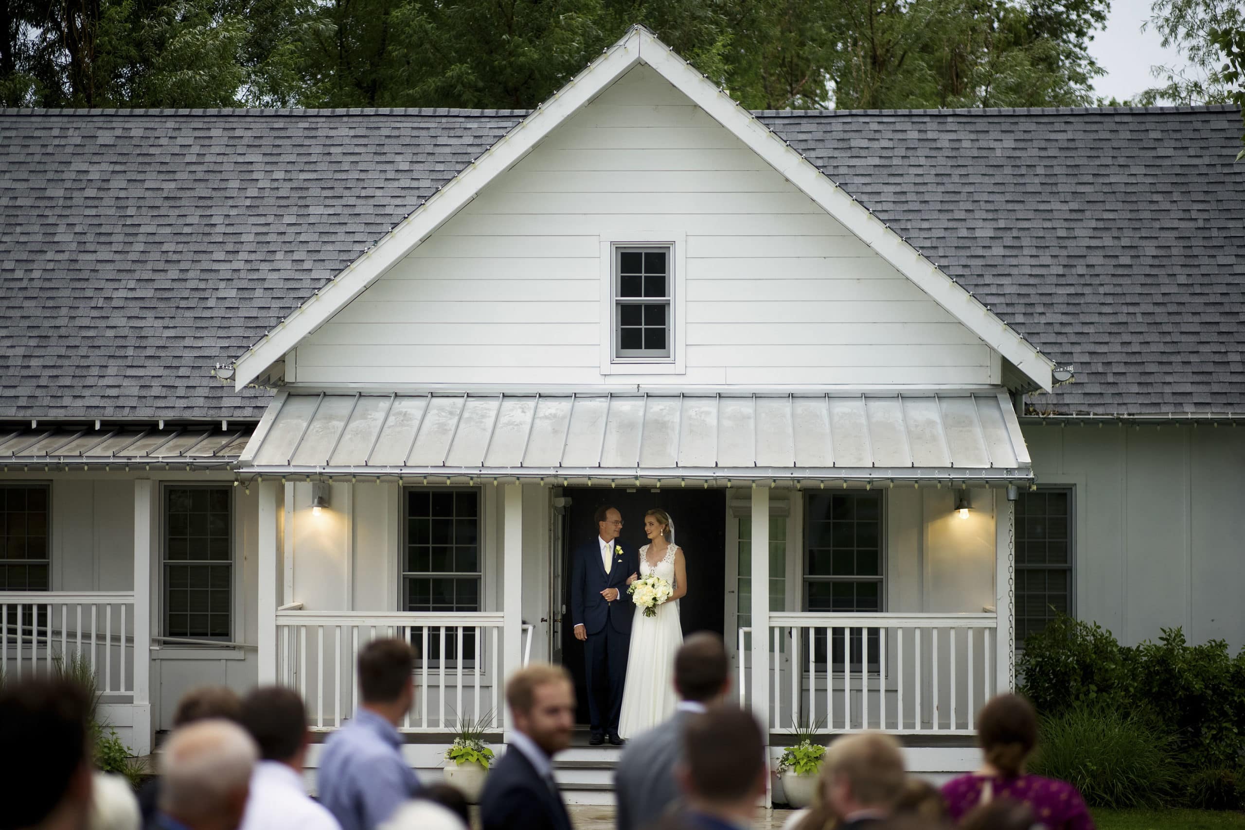 The bride and her father exit the bridal cottage during the wedding ceremony at the barn at raccoon creek