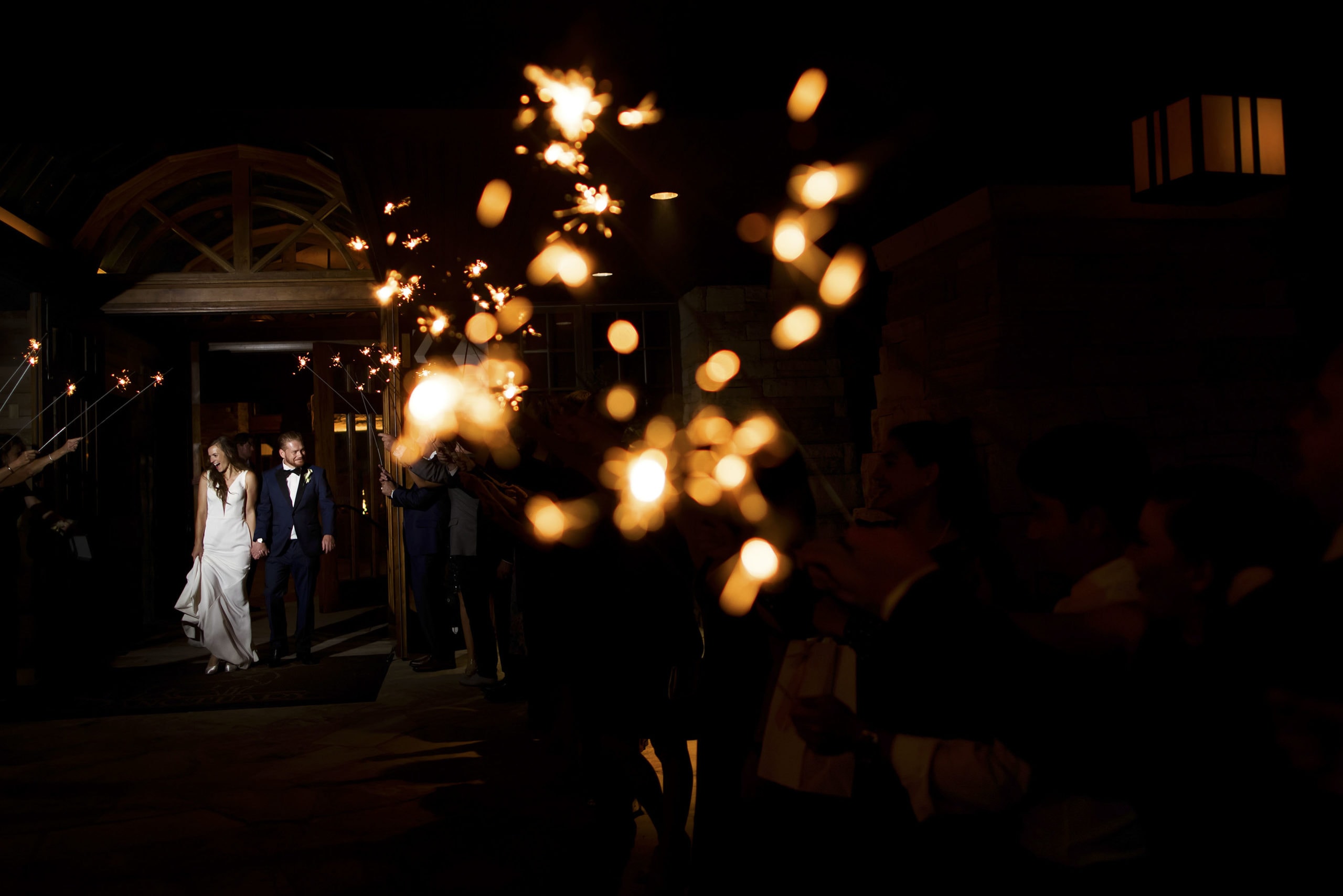 The bride and groom leave their wedding reception through a tunnel of sparklers at Sanctuary