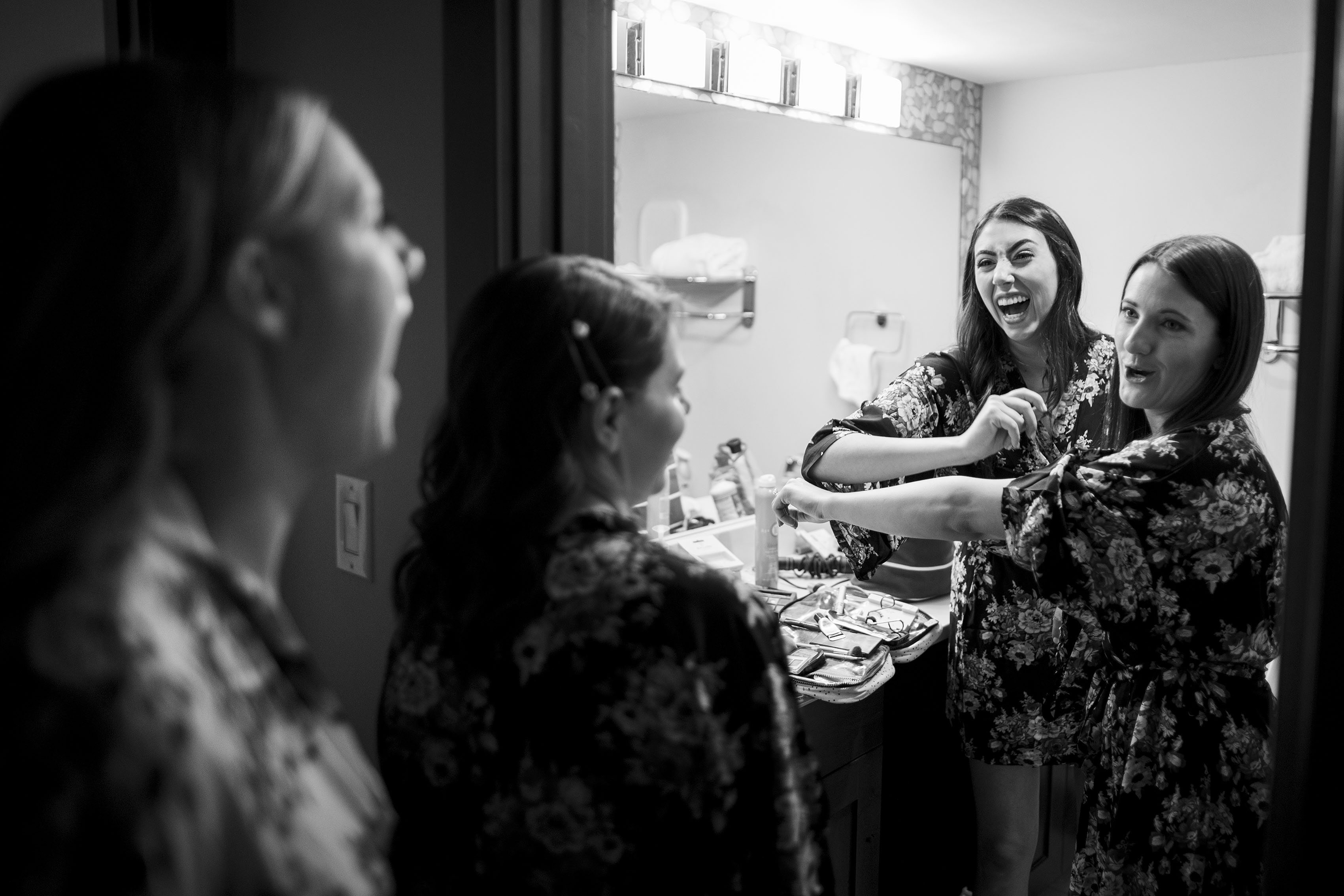 Bridesmaids laugh while doing their makeup before the wedding
