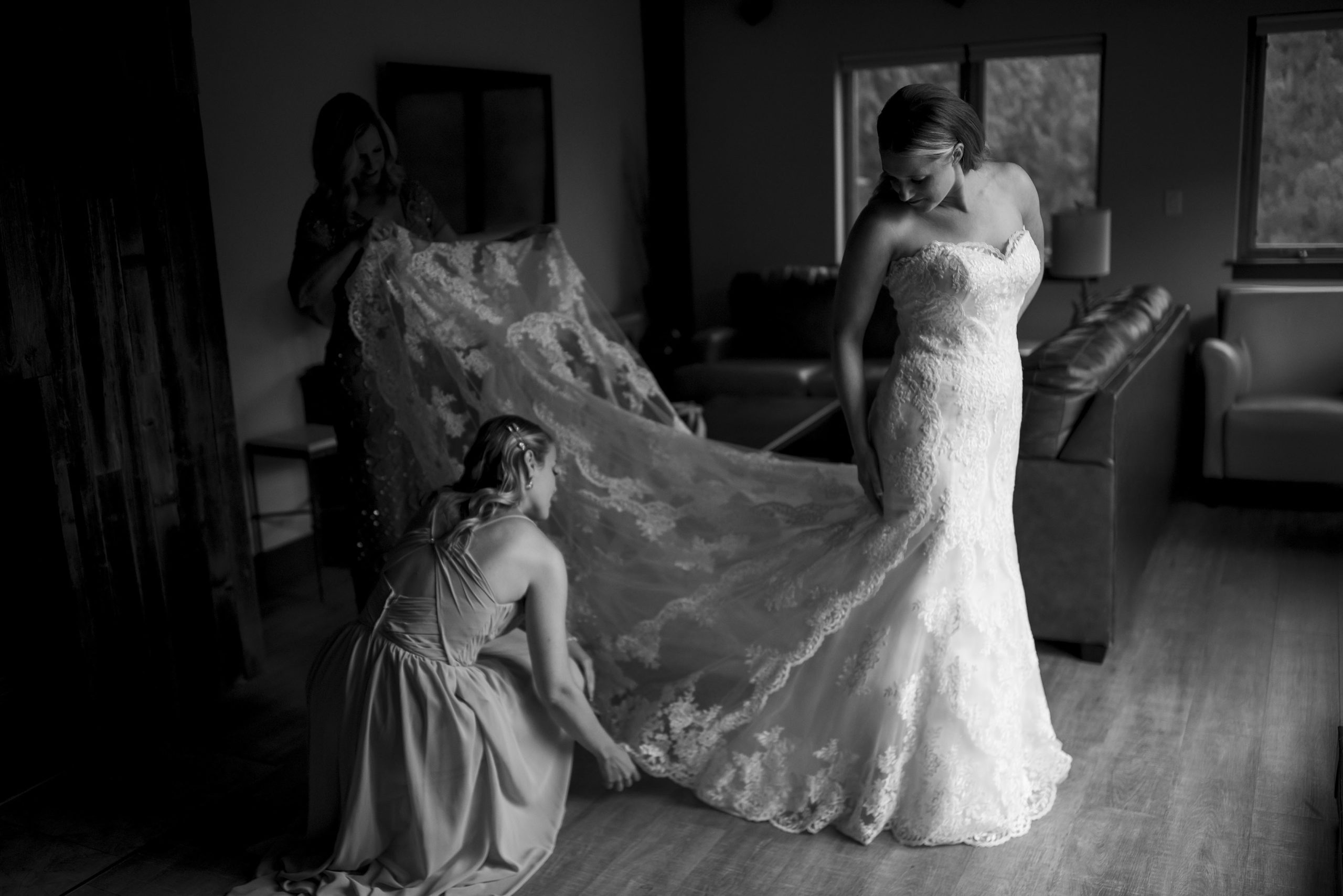 The bride has her wedding dress adjusted while getting ready