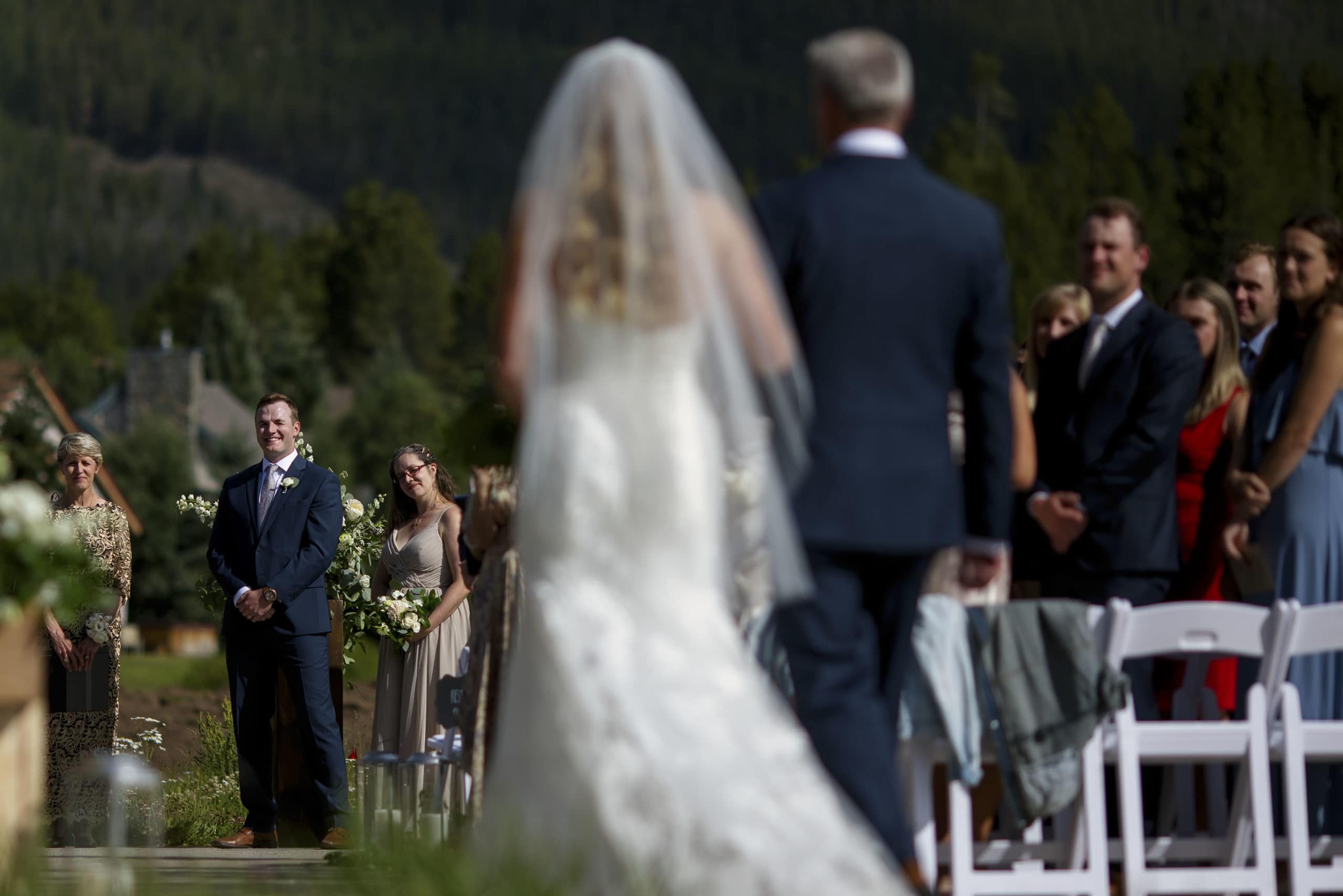 The groom looks on as the bride walks down the aisle during their wedding ceremony at Copper VIsta