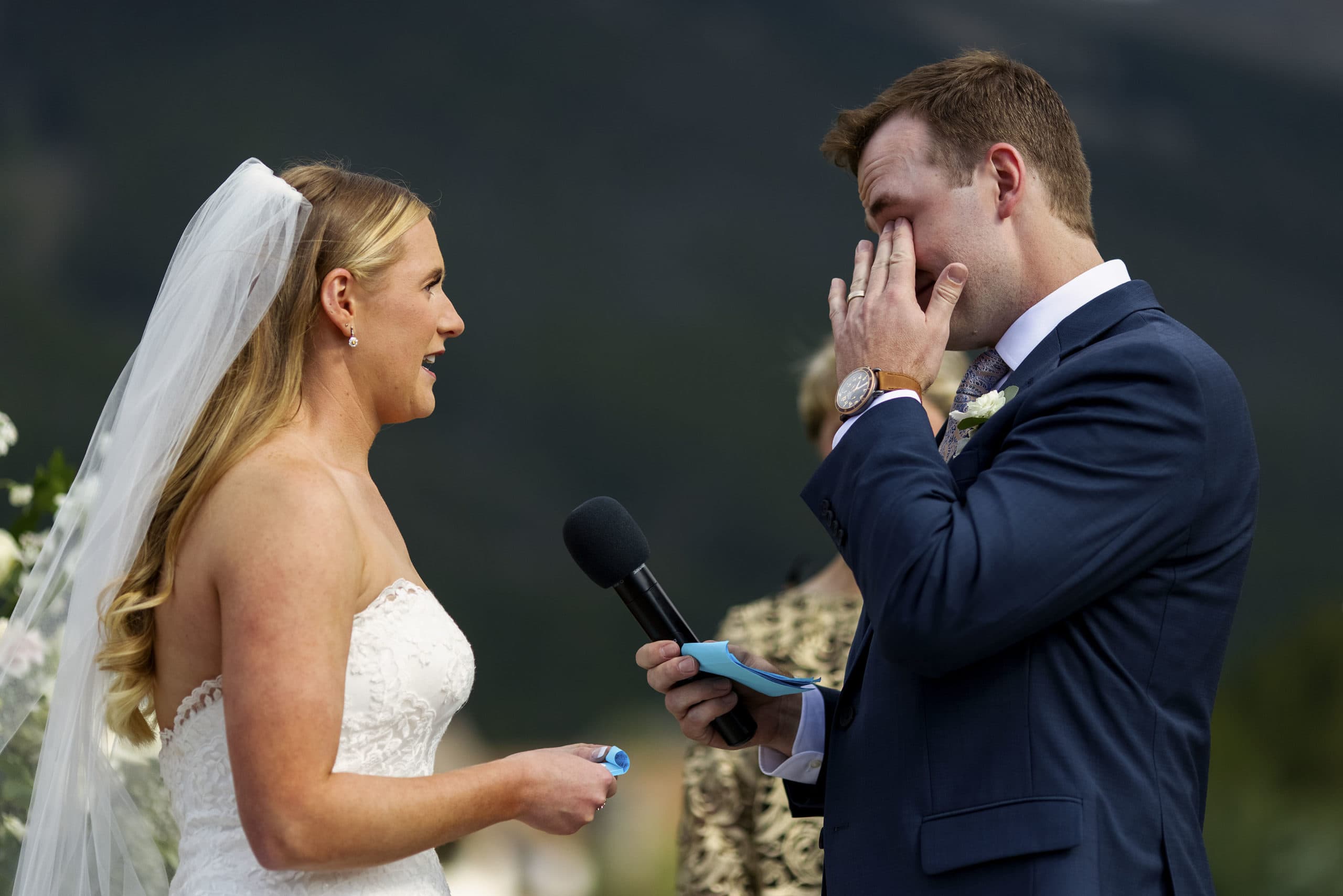 The groom wipes away a tear while the bride reads her vows