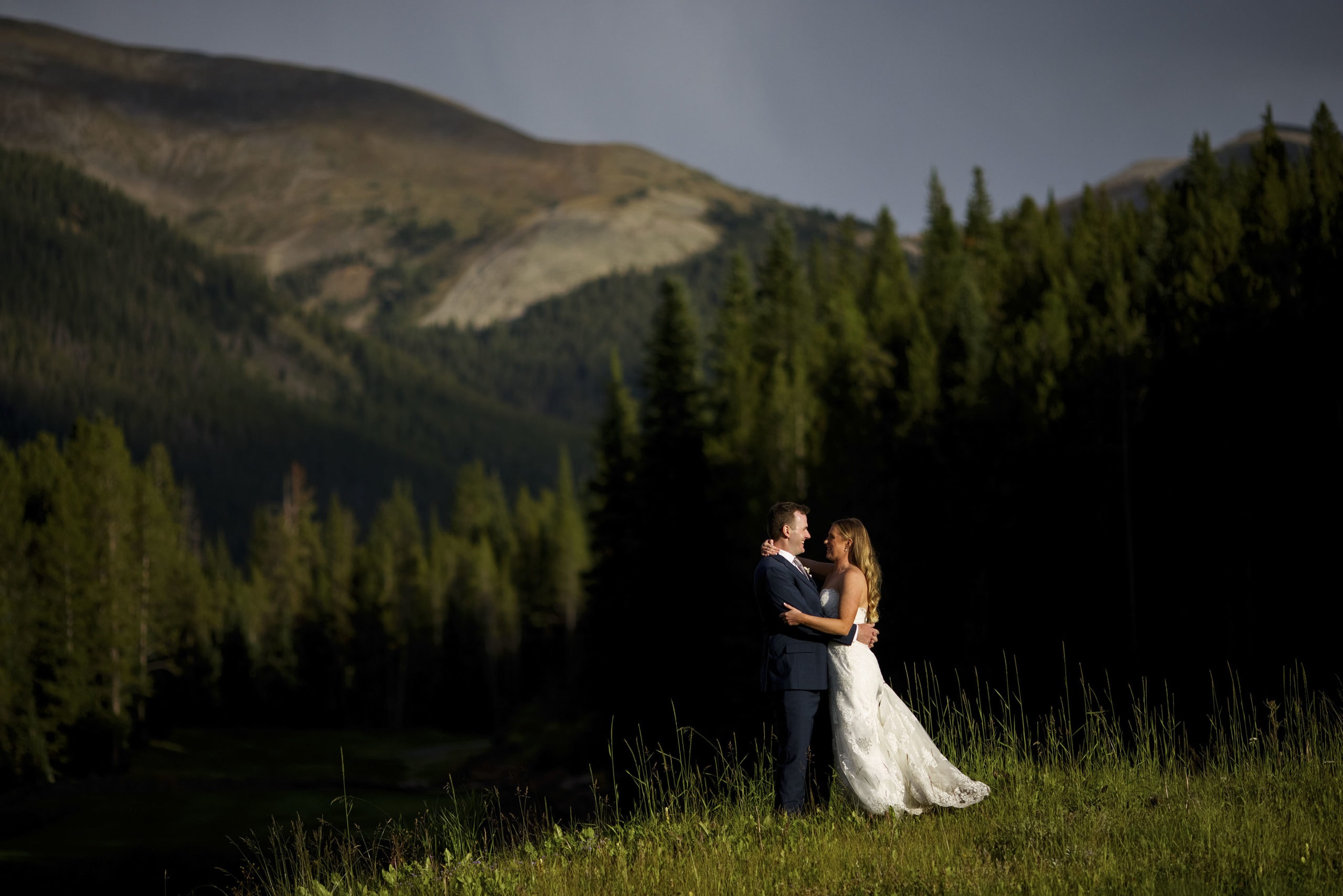 The groom and bride embrace during golden hour with the Tenmile range in the background