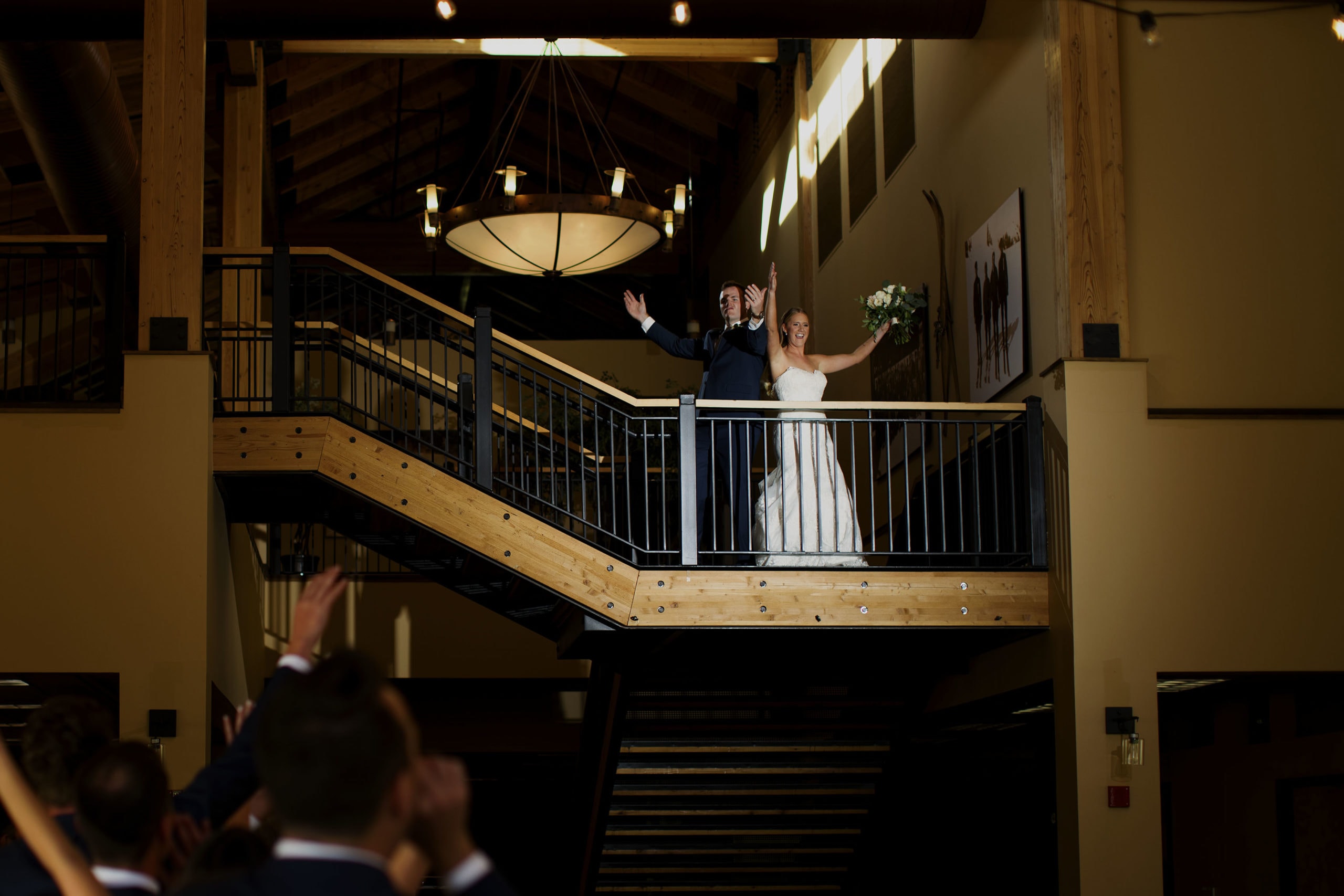 The bride and groom wave to guests from a balcony as they’re introduced in the Grand Hall at Copper Mountain