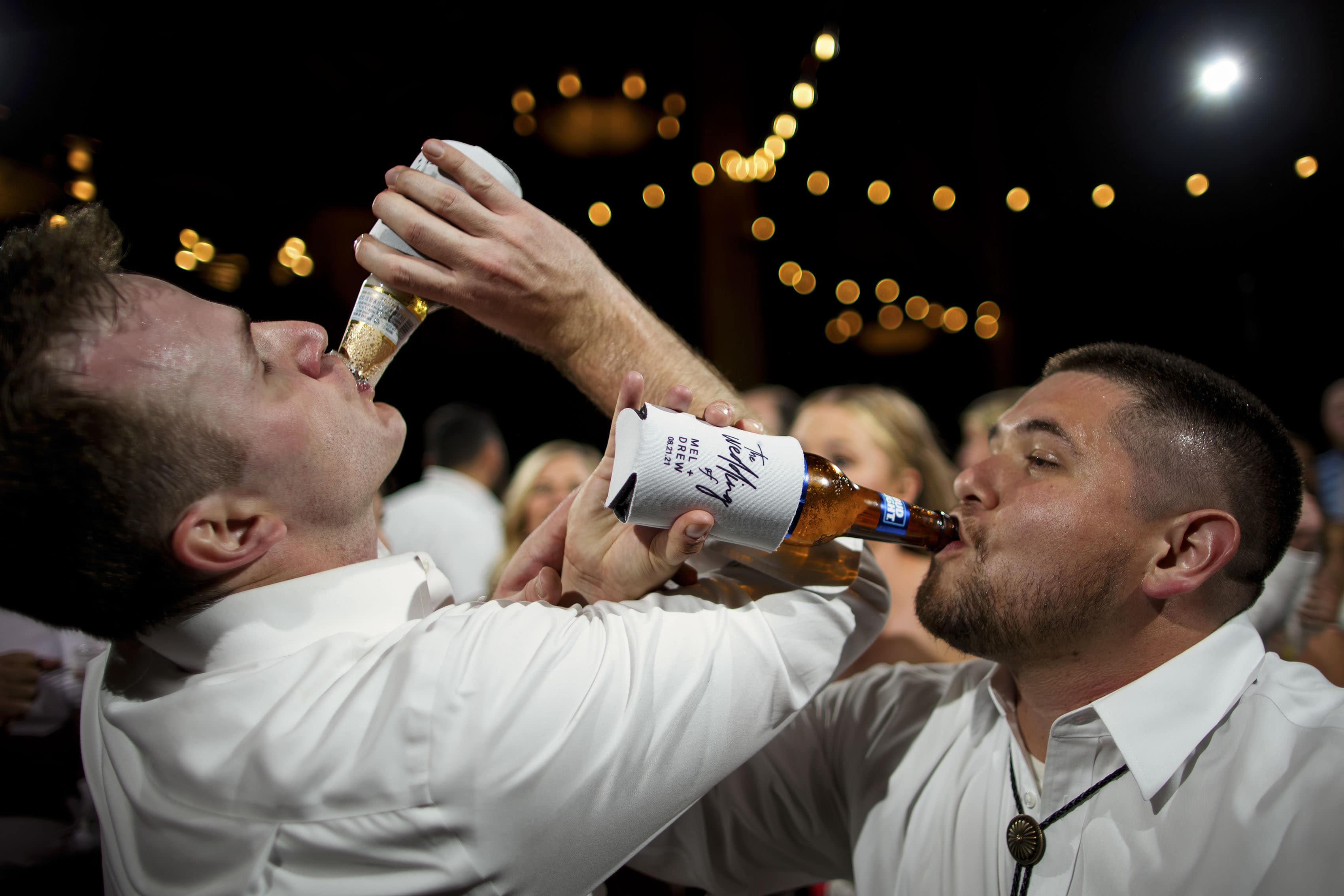 Guests drink beers together during a wedding reception in the Grand Hall at Copper Station