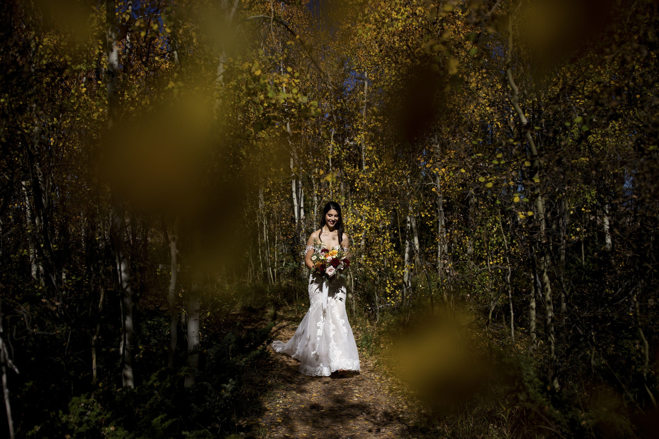 The bride walks through a yellow aspen grove to the ceremony site at Granby Ranch