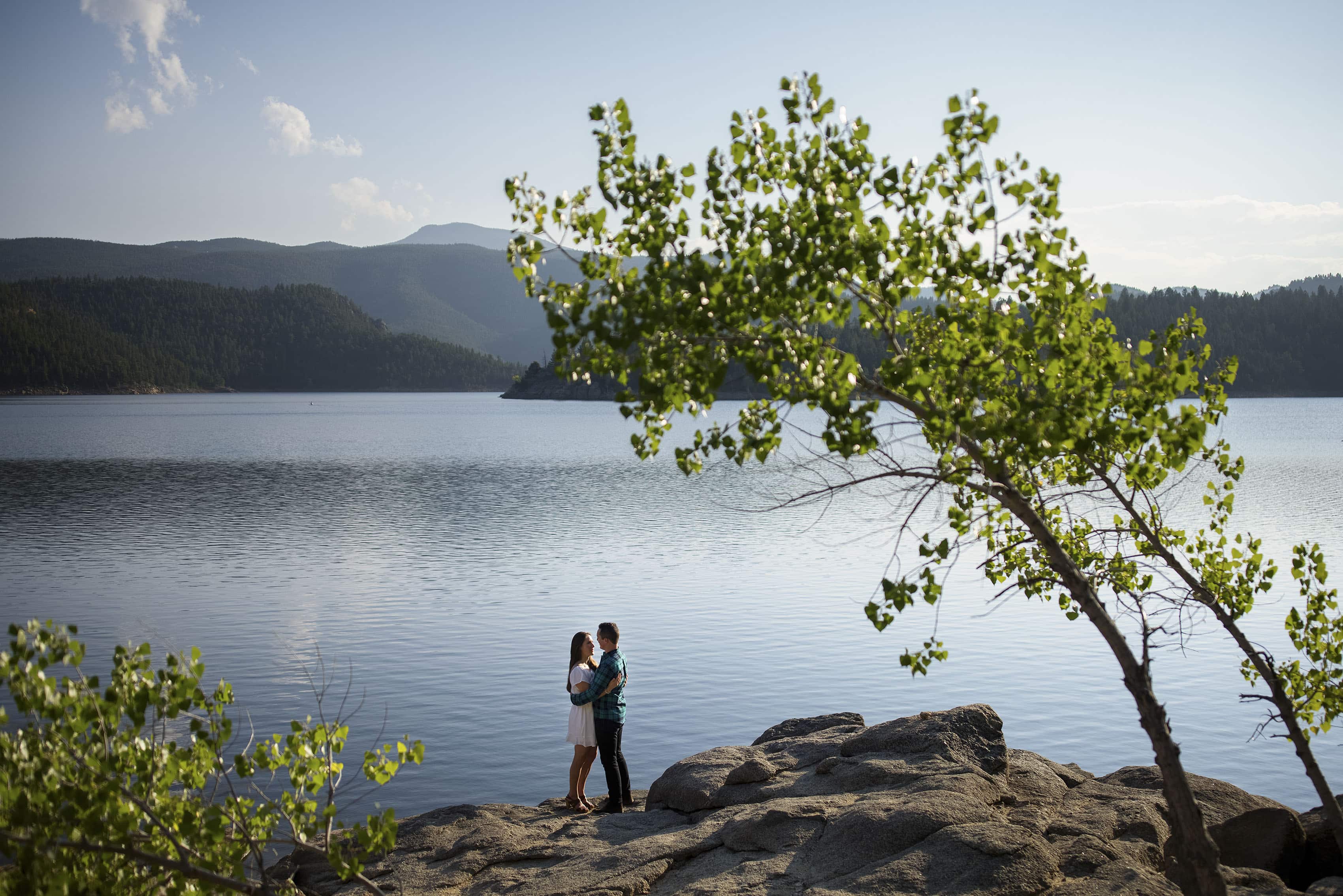 A couple poses near the water at Gross Reservoir during engagement photos