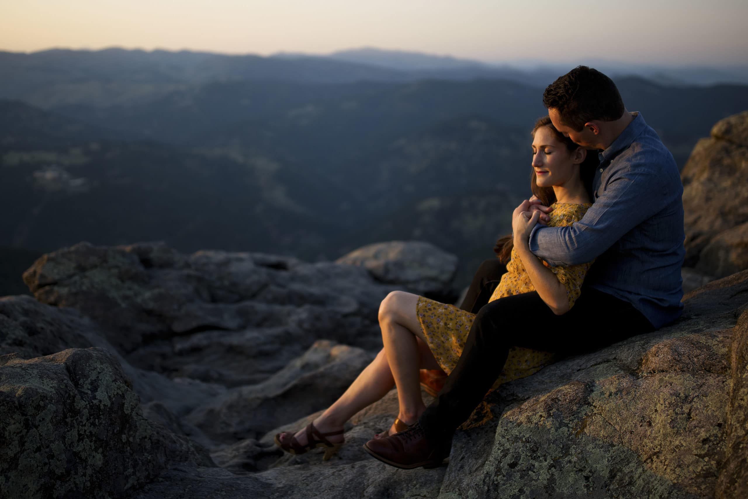 A couple sits on the rocks at Lost Gulch Overlook during their engagement photos