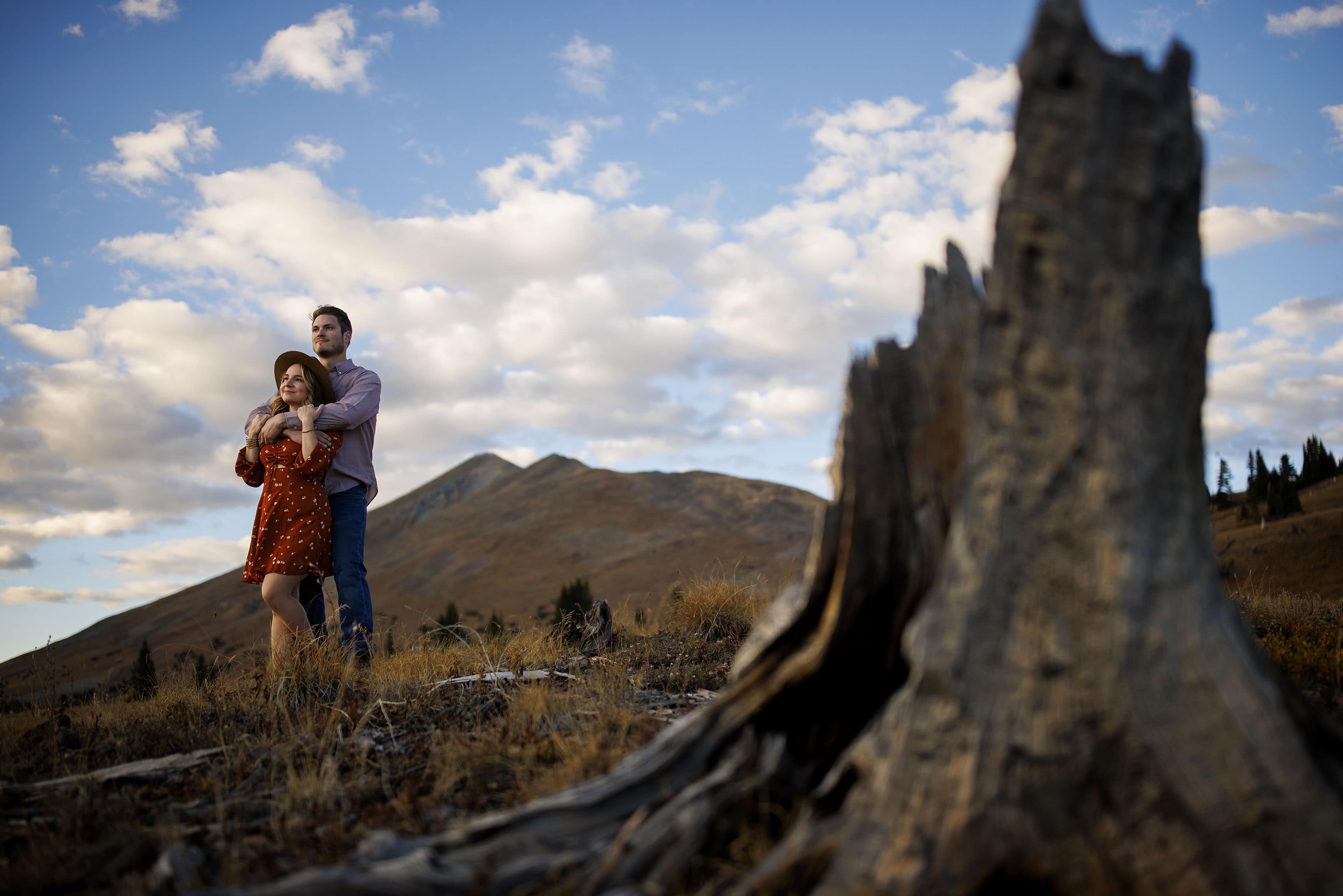 An engaged couple hugs each other while they enjoy the sunset on Breas Pass in Breckenridge