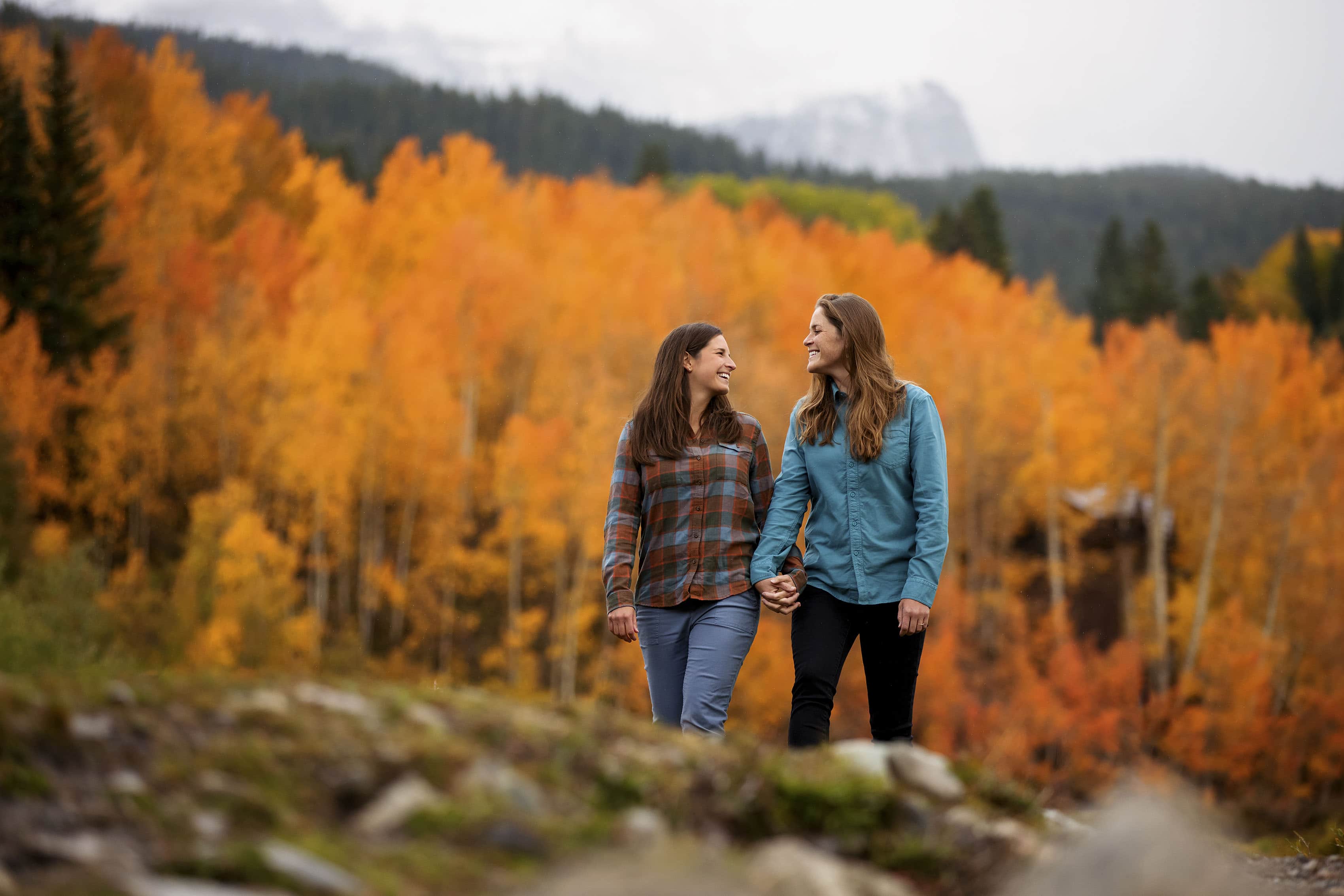 Cait and Anna walk together near golden aspen trees in Ophir