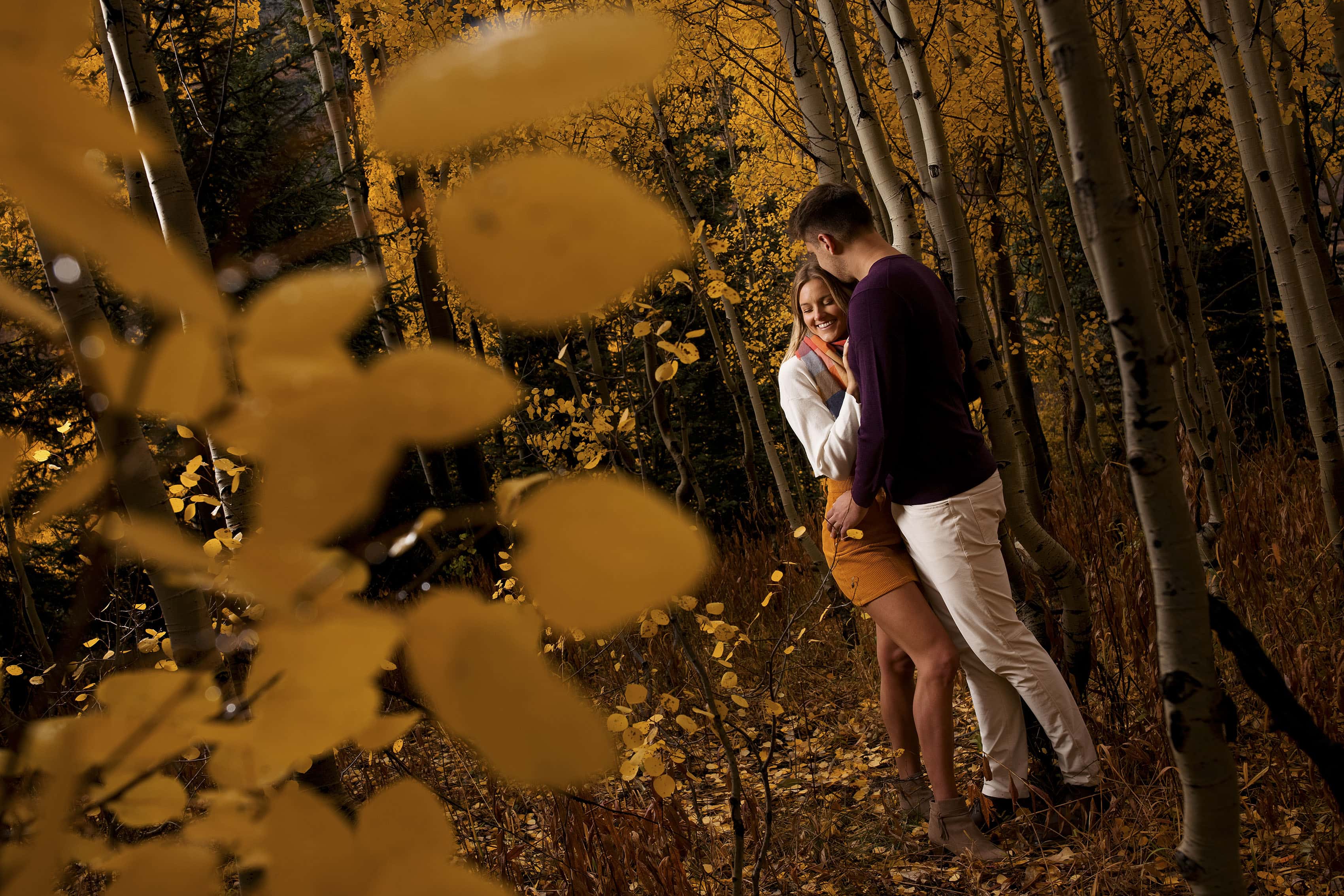 Willy kisses Kelly’s forehead in an aspen grove during their fall engagement session