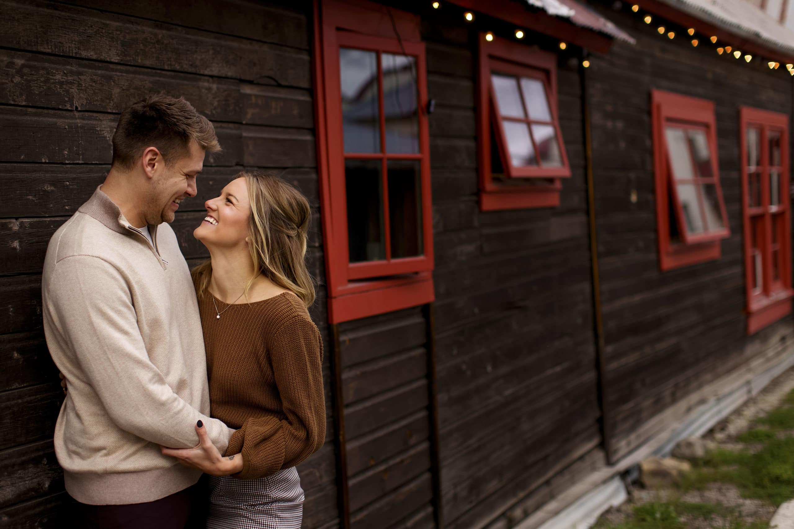 A cute couple shares a laugh outside The Dogwood in Crested Butte during their engagement photos